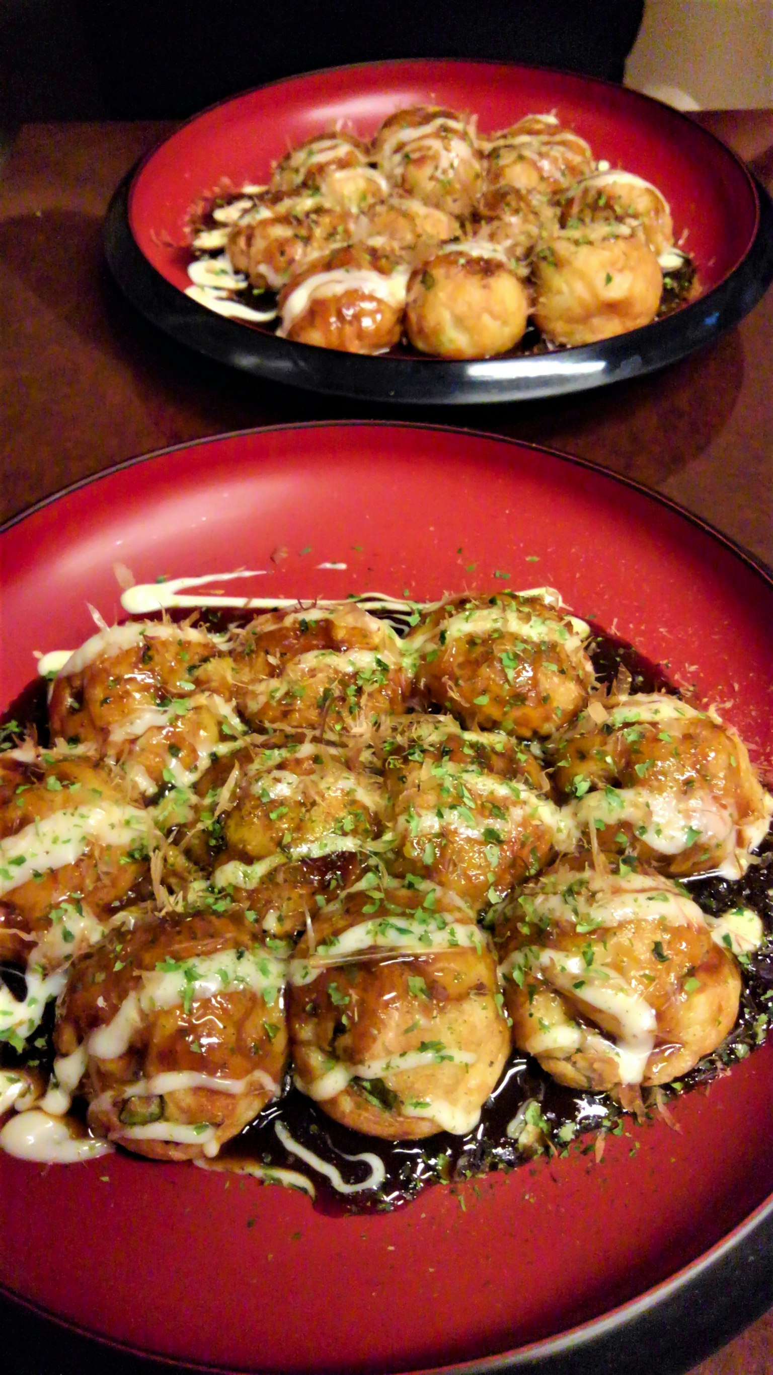 Piatto di takoyaki con salsa e guarnizione verde