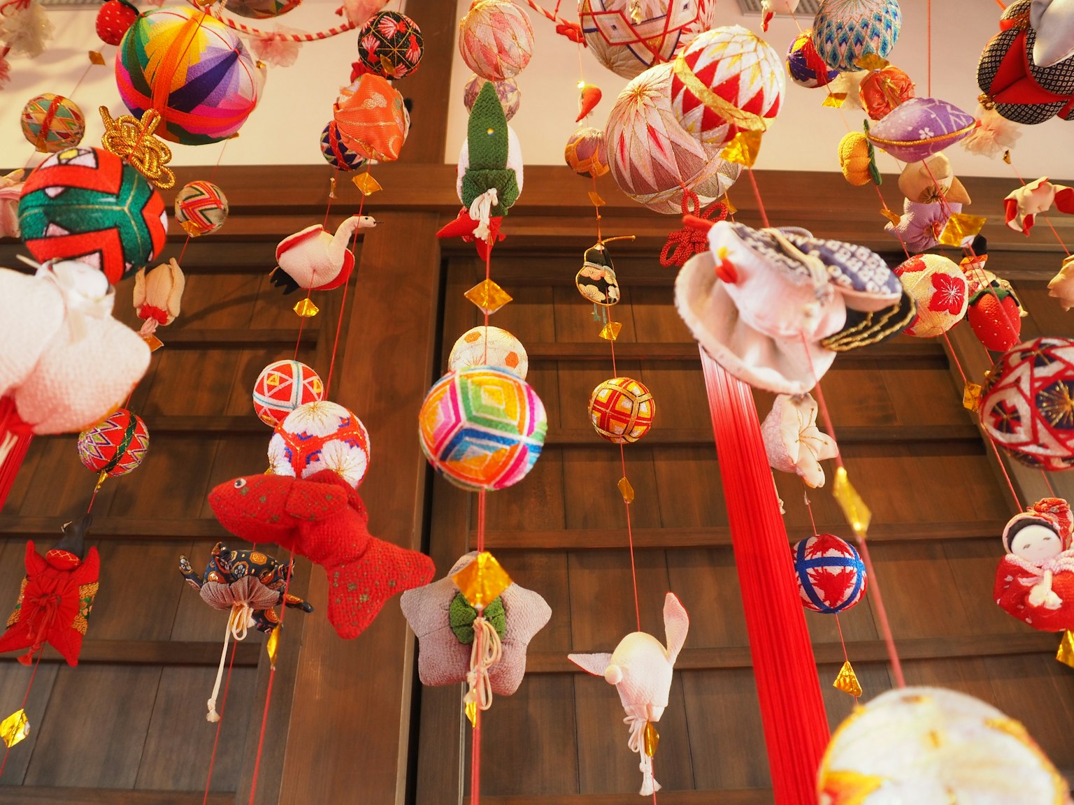 Decoraciones colgantes japonesas tradicionales coloridas exhibidas en una pared de madera