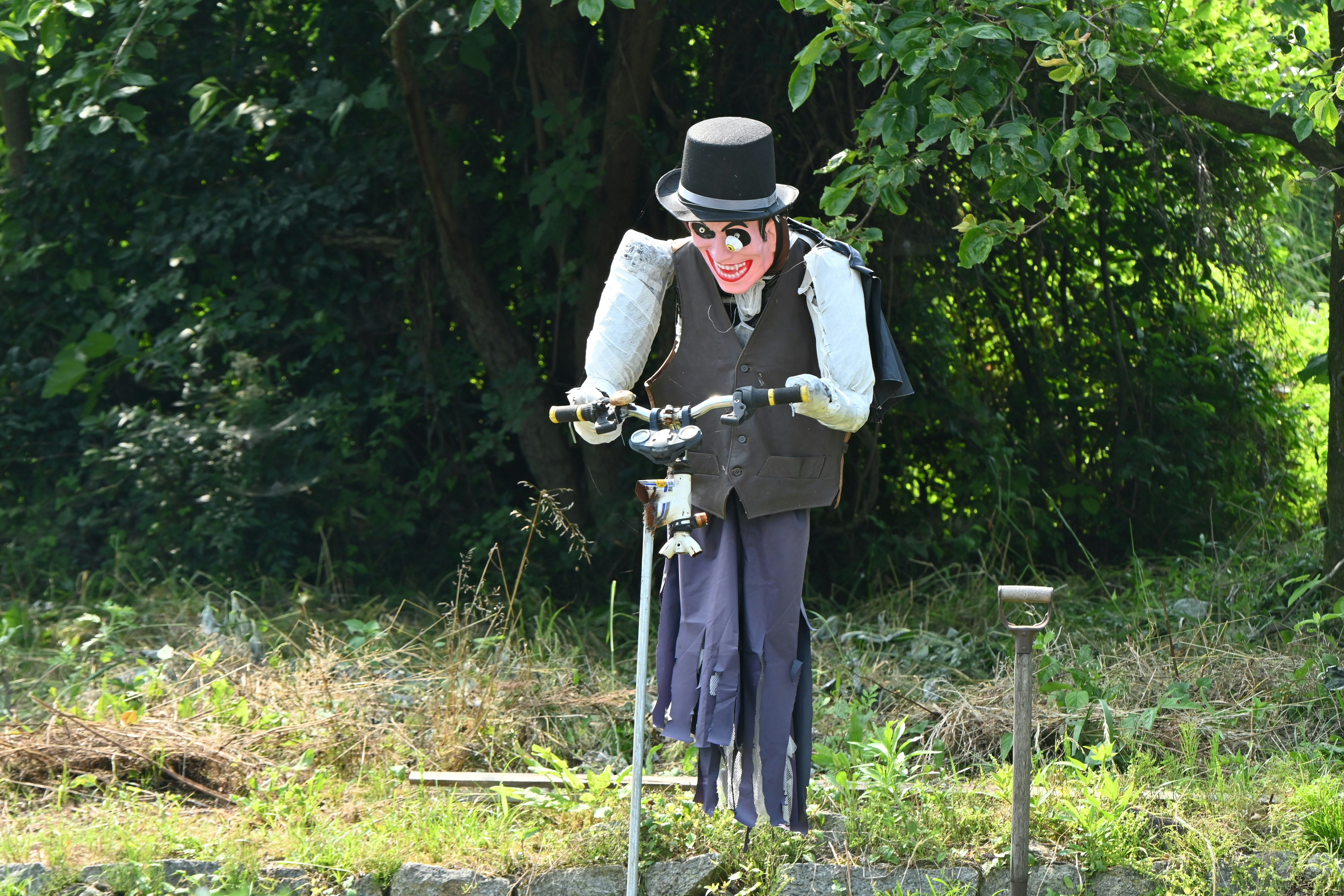 costumed rider with a bicycle in a green garden