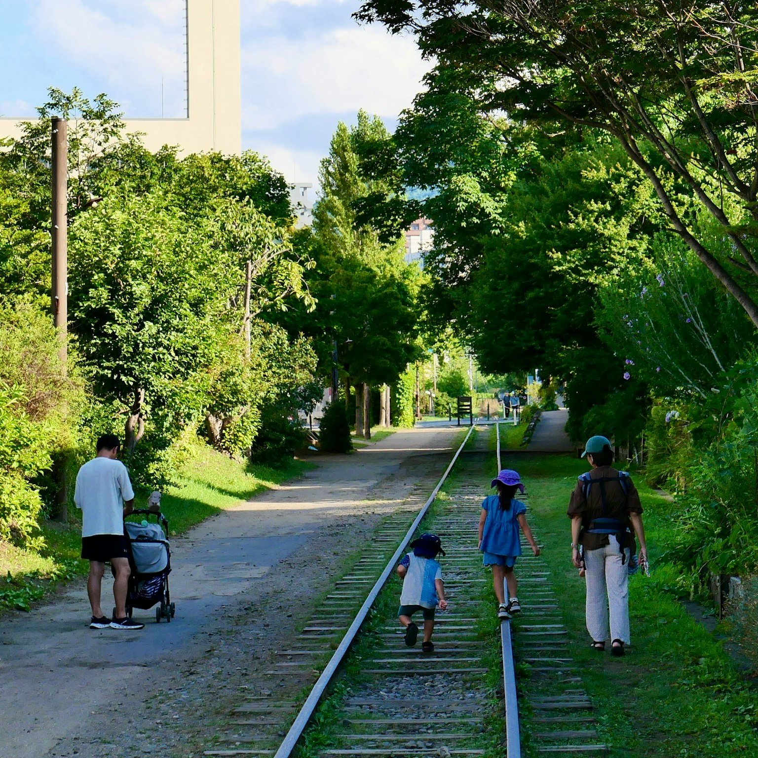 Familie, die entlang eines grünen Parkwegs neben alten Gleisen spaziert