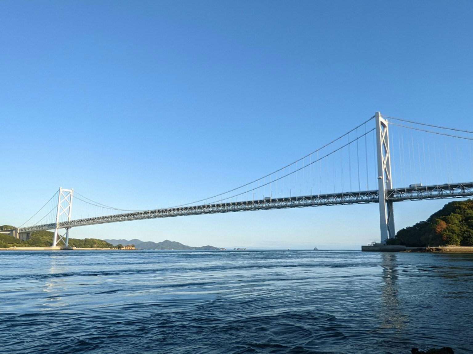 สะพานแขวนที่สวยงามใต้ท้องฟ้าสีฟ้าใสกับน้ำที่สงบ