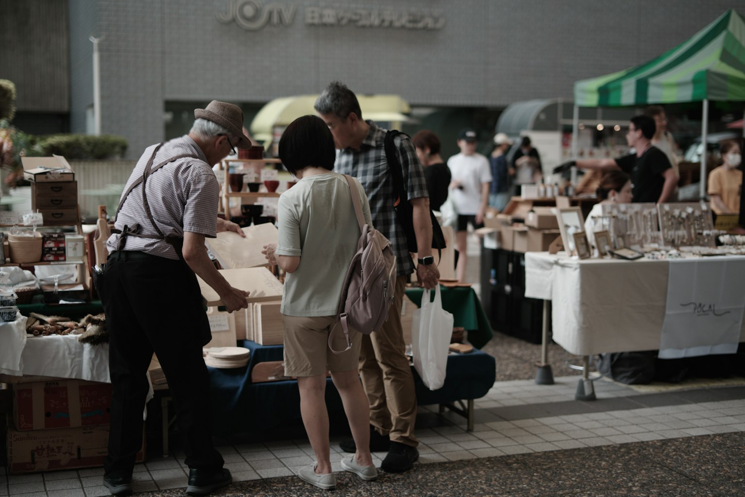 Persone che sfogliano articoli in un mercato con tavoli allineati