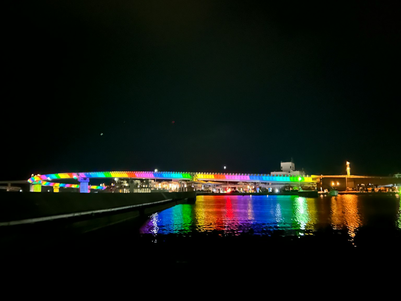 夜晚彩色燈光照亮的橋在水面上反射