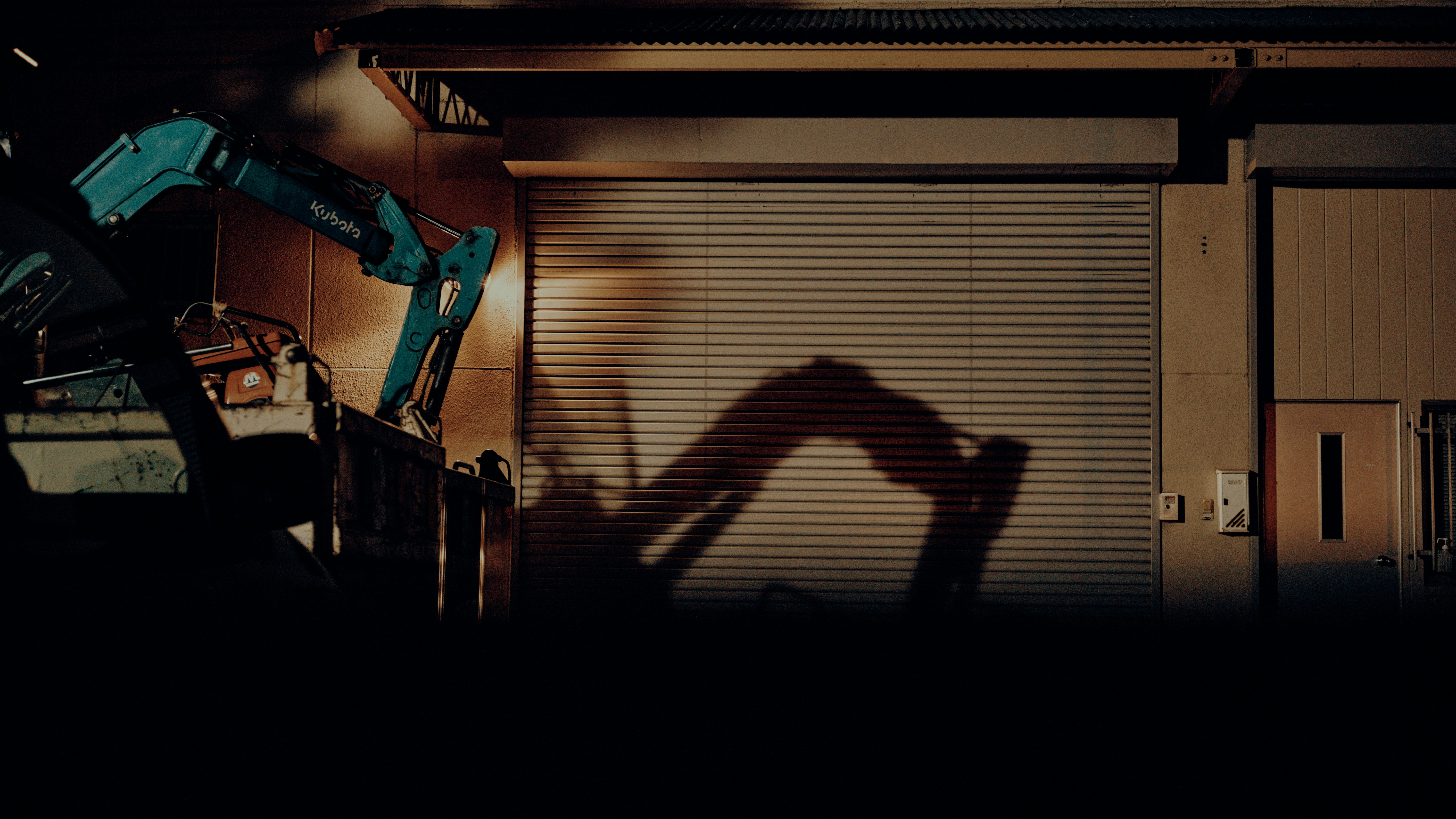 construction machinery and a shadow in front of a shuttered garage image