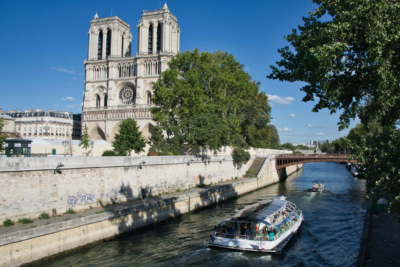 Catedral de Notre Dame a lo largo del río Sena con un barco turístico