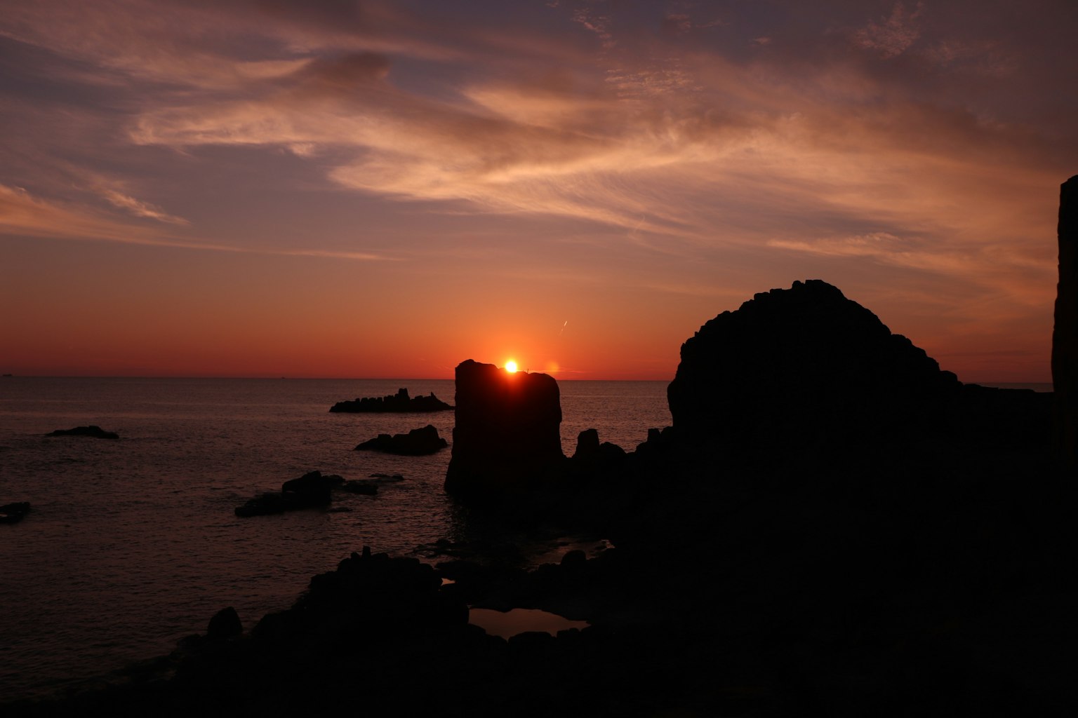Silhouette of rocks with sunset over the sea
