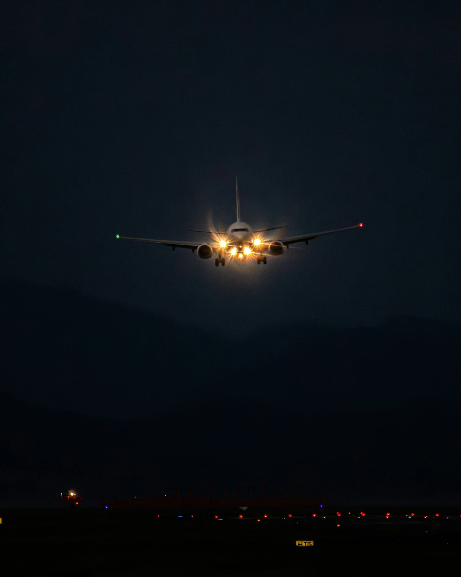Lumières d'atterrissage d'un avion brillantes dans le ciel sombre