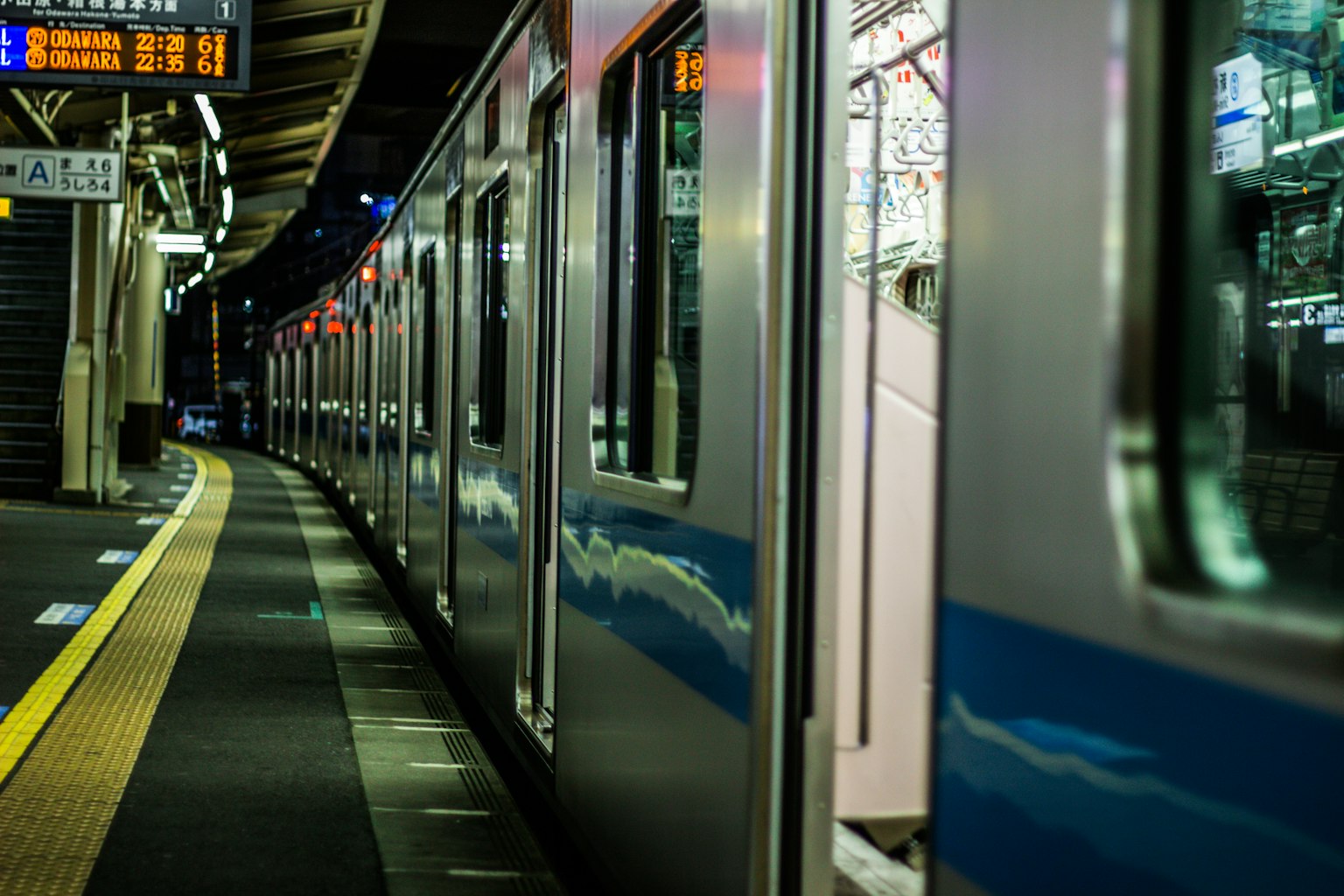 Vista delle carrozze del treno in una stazione di notte con luci sulla piattaforma