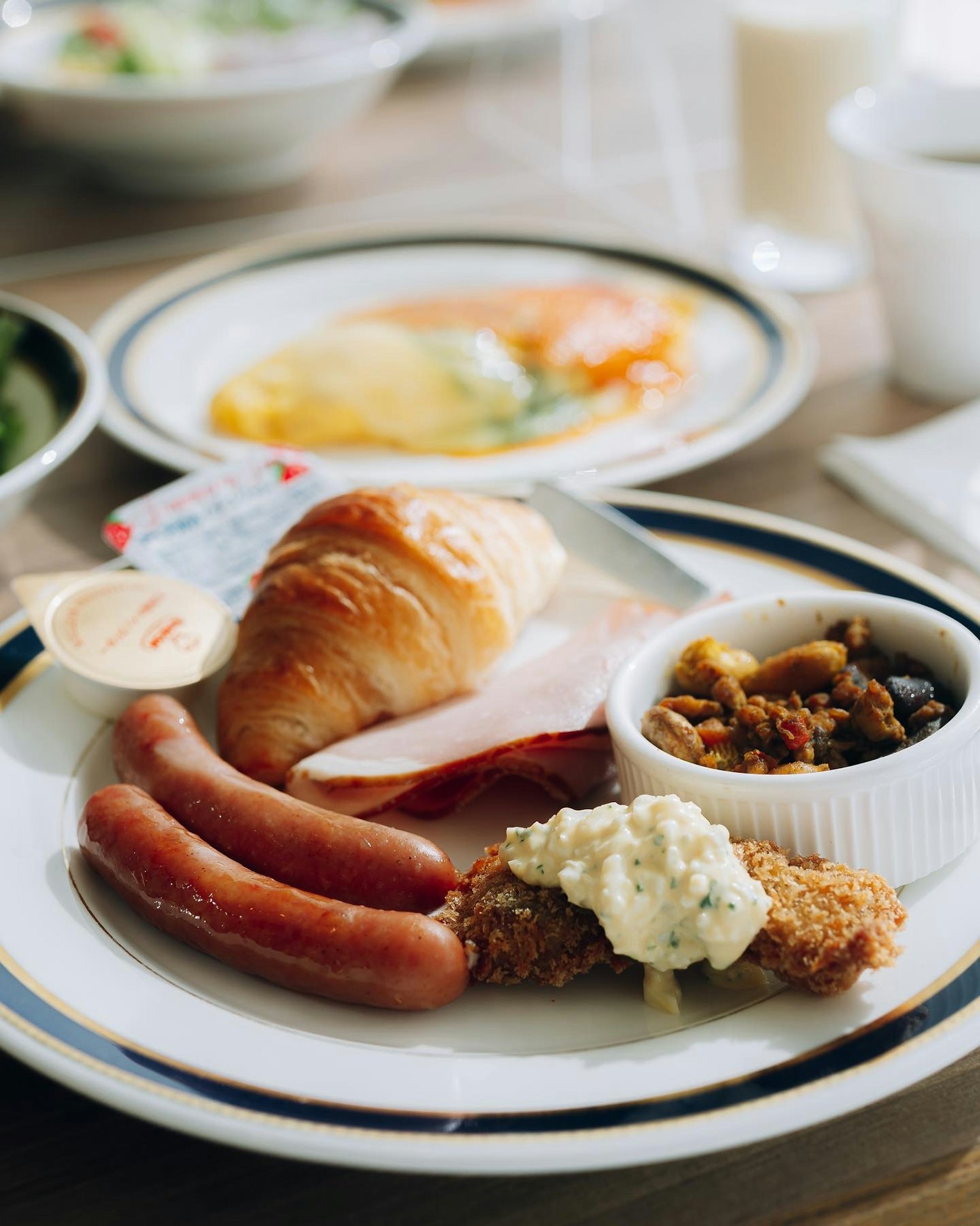 Piatto per colazione con salsicce croissant insalata omelette e una piccola ciotola di frutta