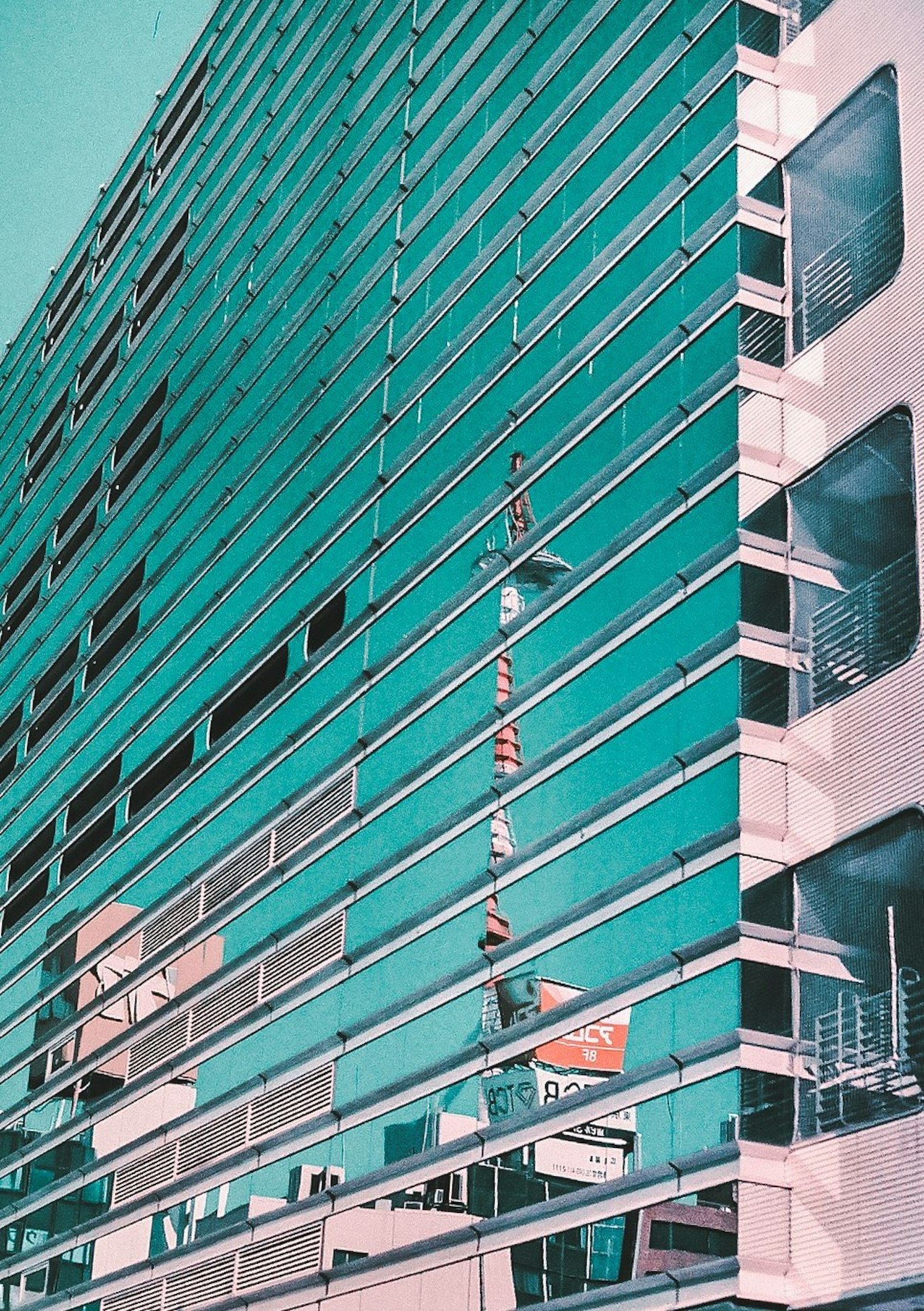 Facciata di un edificio moderno coperta in vetro teal con listelli orizzontali