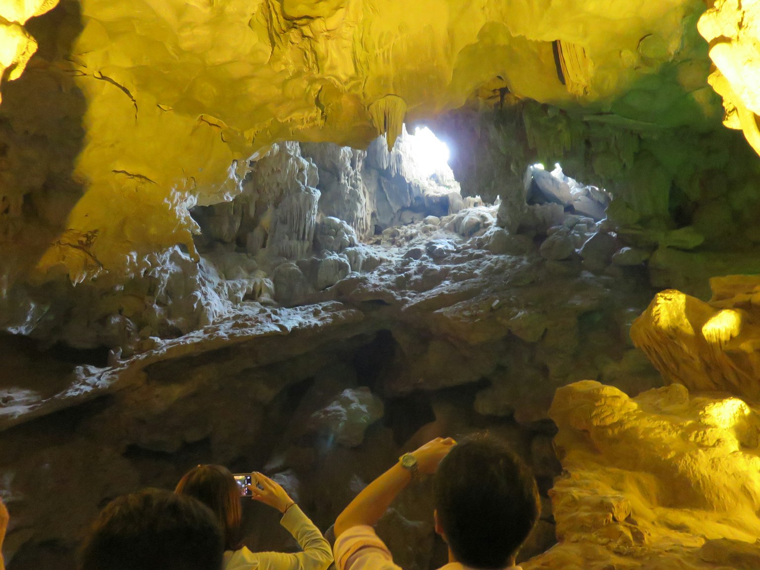 Immagine dell'interno di una grotta con luce che filtra Persone che scattano foto con smartphone