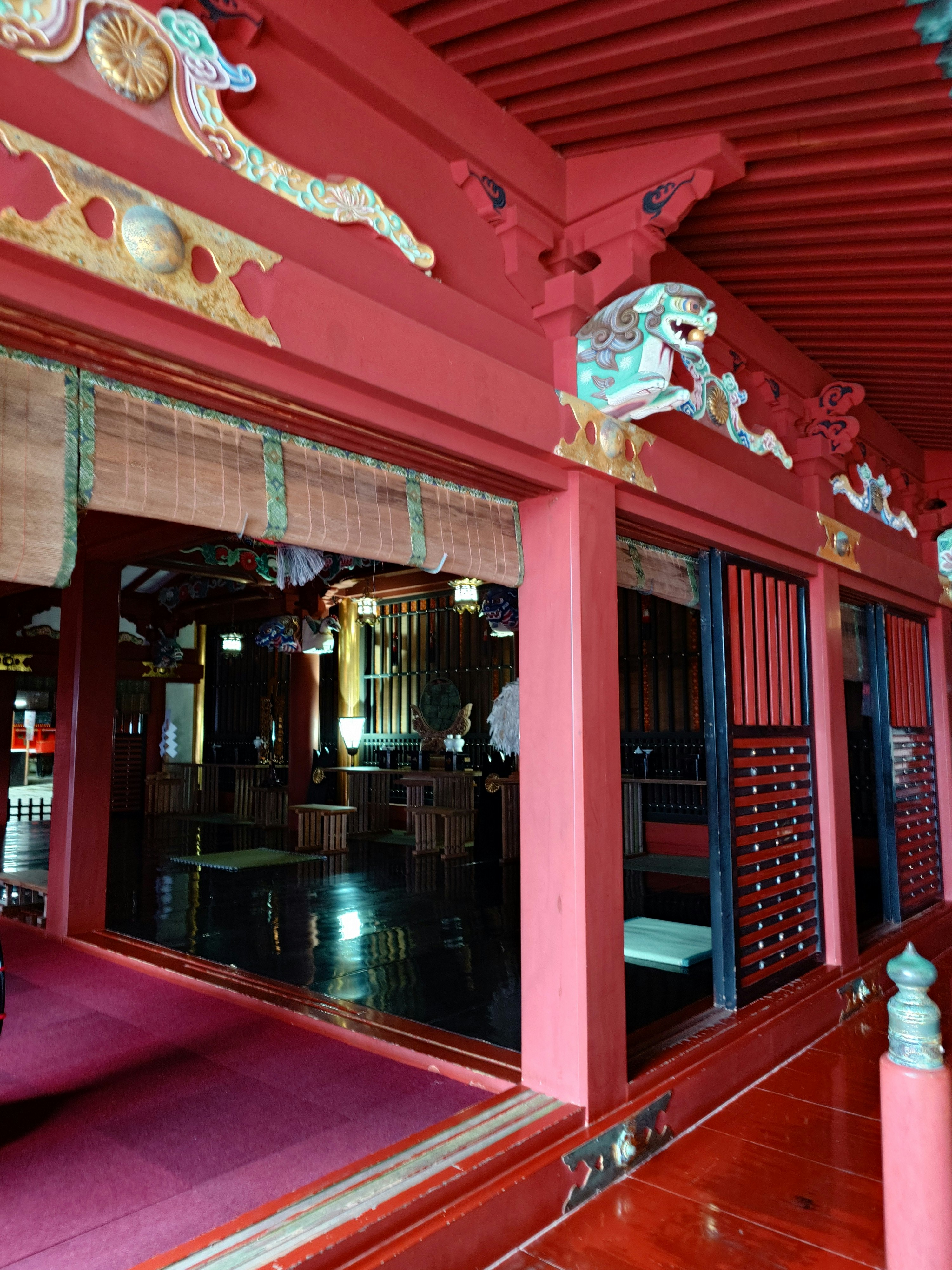 Vue intérieure d’un couloir de temple aux poutres rouges et sculptures