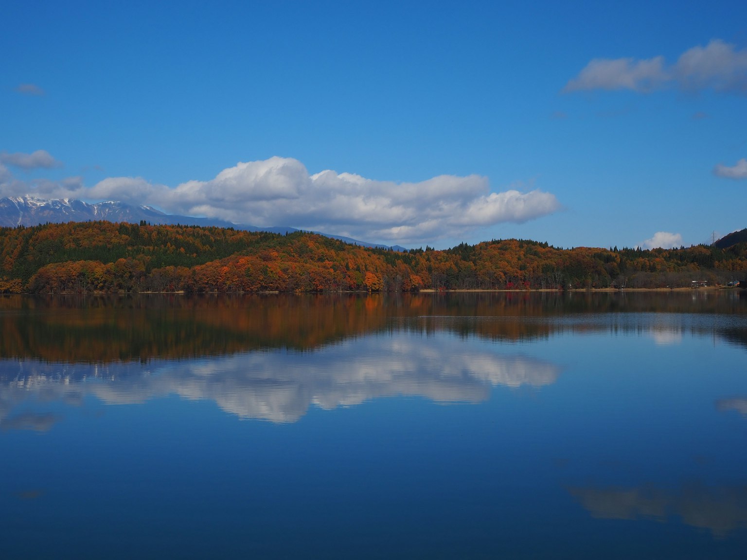 Scenic lake view with autumn foliage reflecting against a clear blue sky