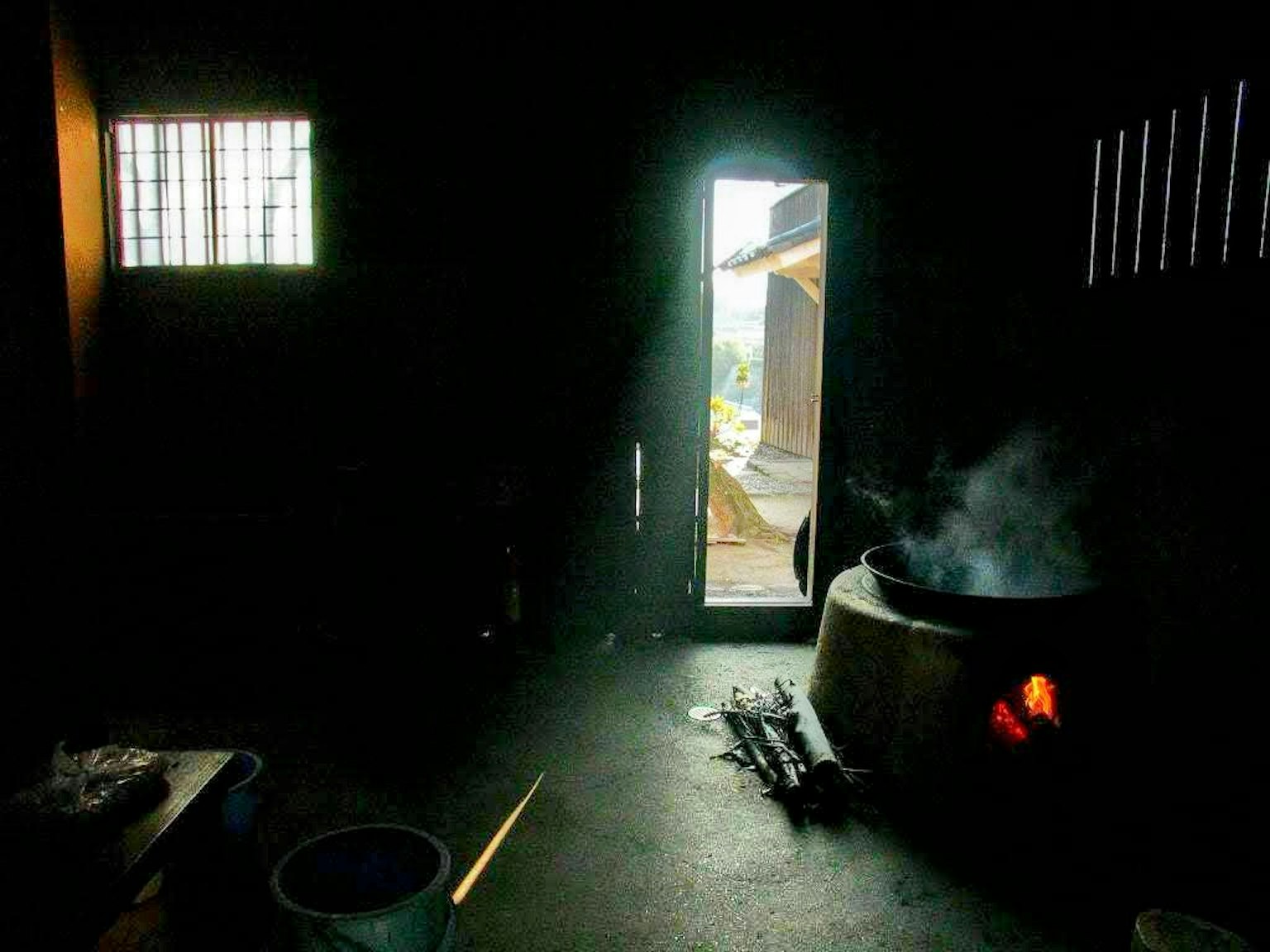Stanza buia con un vaso fumante e luce proveniente da una porta aperta