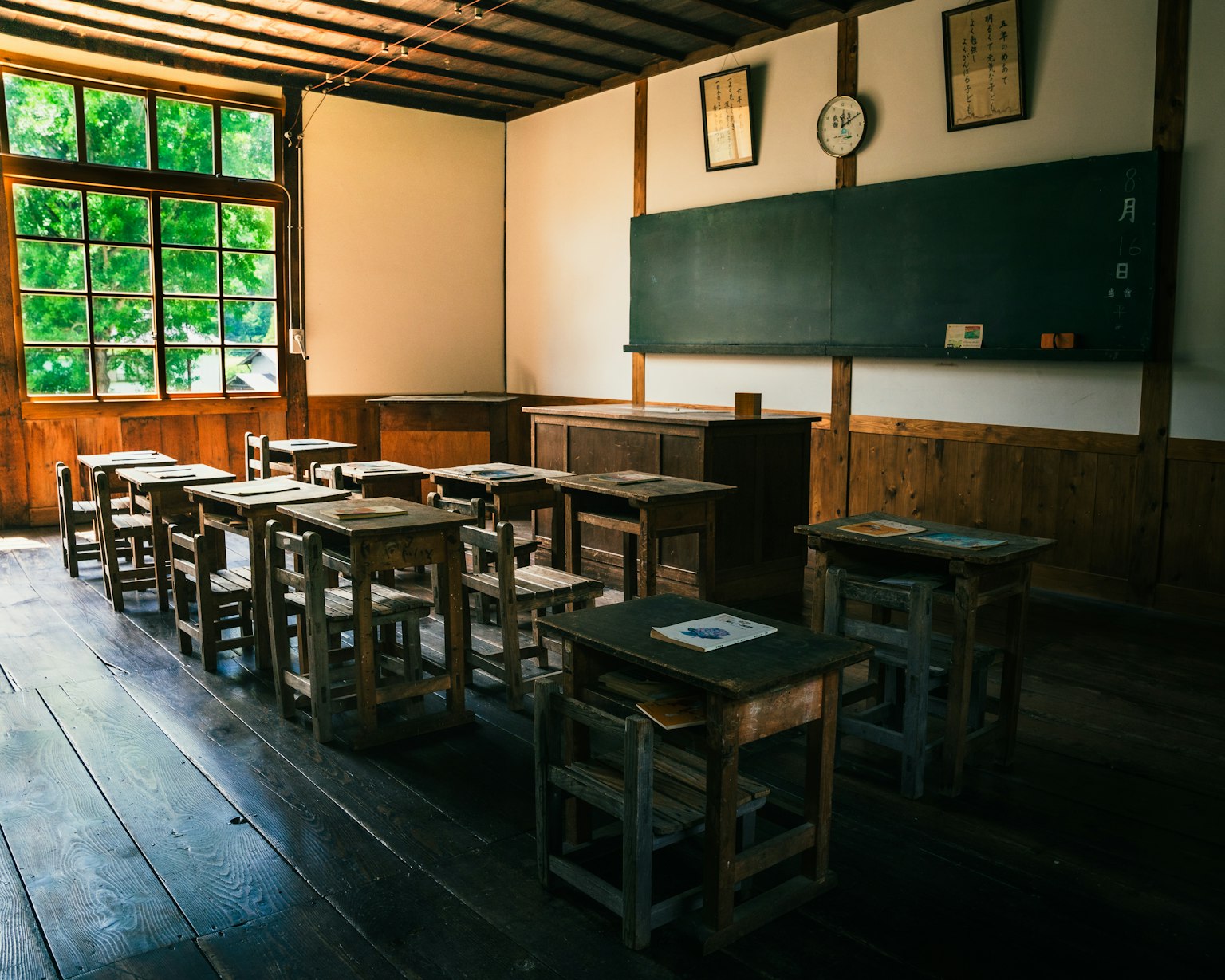 Interior de un aula antigua con escritorios y sillas de madera luz natural de las ventanas verdes