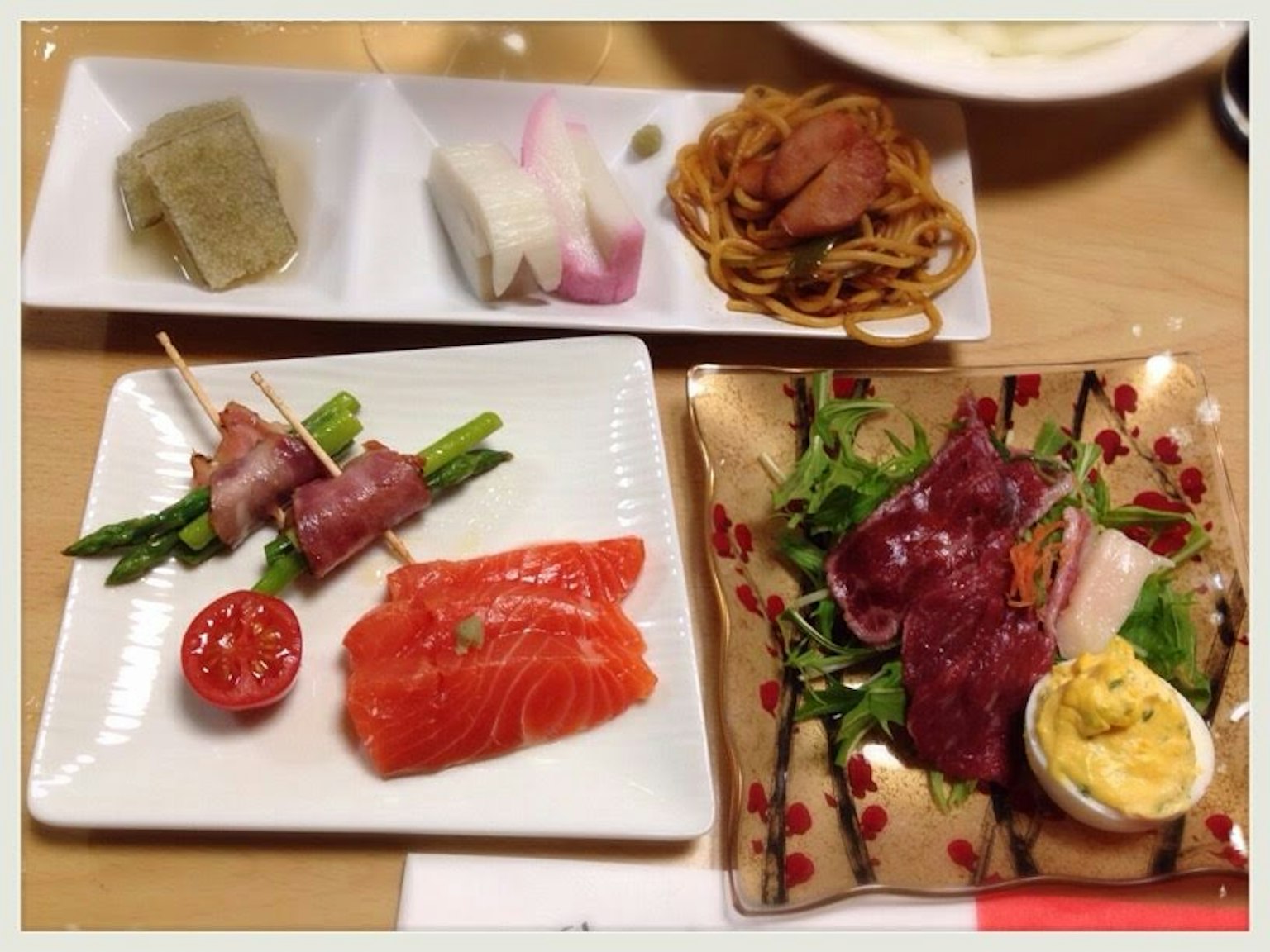 Ein Set aus bunten Gerichten mit frischem Lachs-Sashimi und mit Speck umwickelten Spargeln