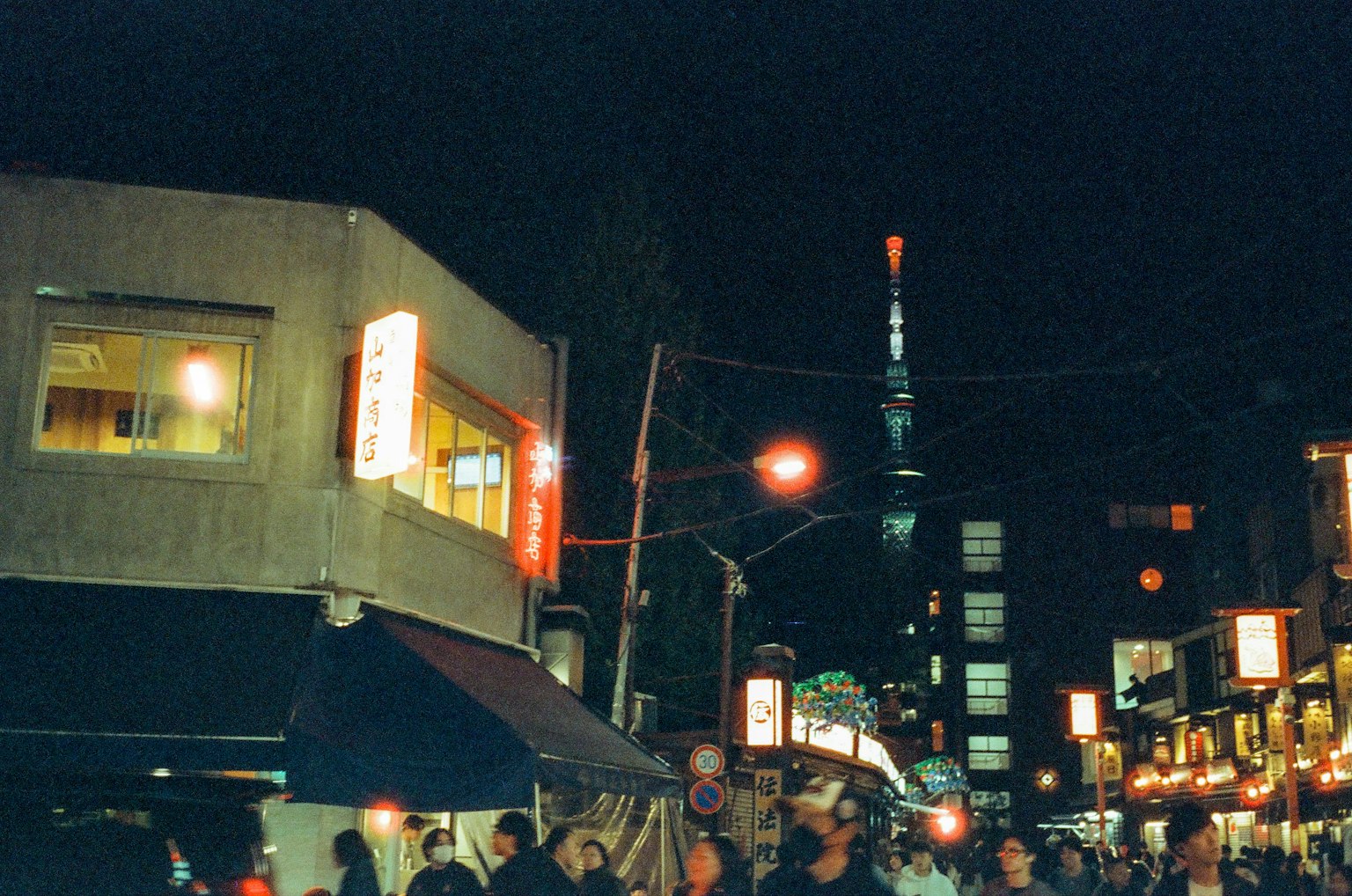 Tokyo Tower illuminated at night with bustling street scene