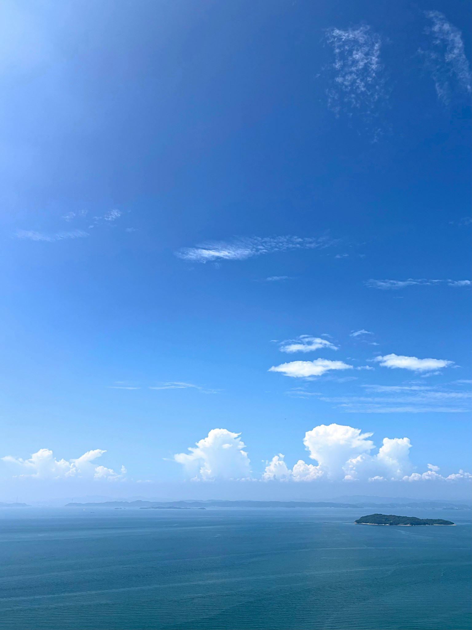 广阔的蓝天和海洋景观，白云飘浮