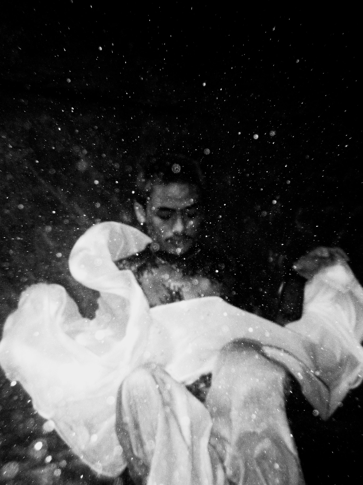 Une personne tenant un tissu blanc immergée dans l'eau dans une image en noir et blanc