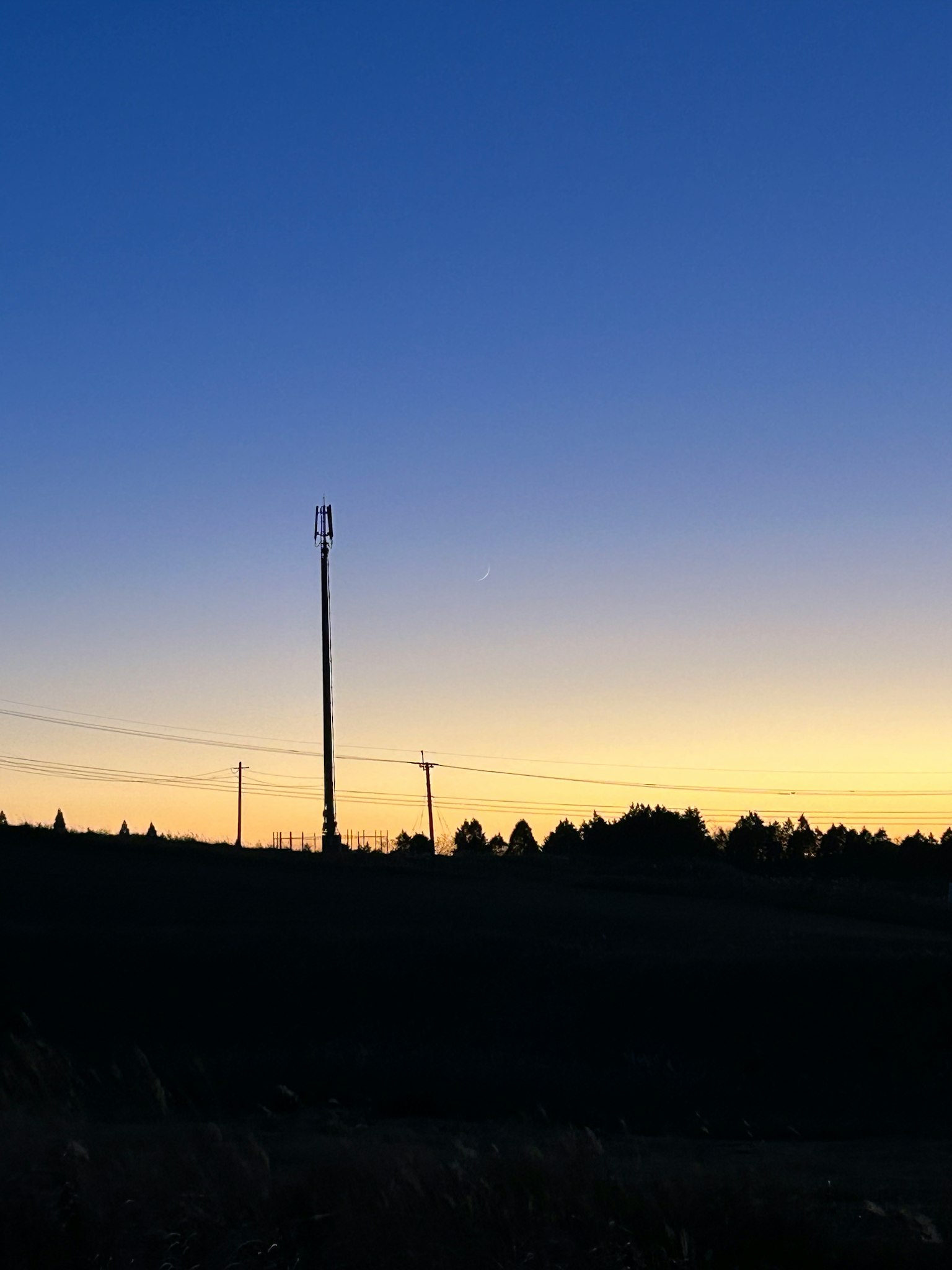 Silhouette eines Strommasts und Drähte bei Dämmerung