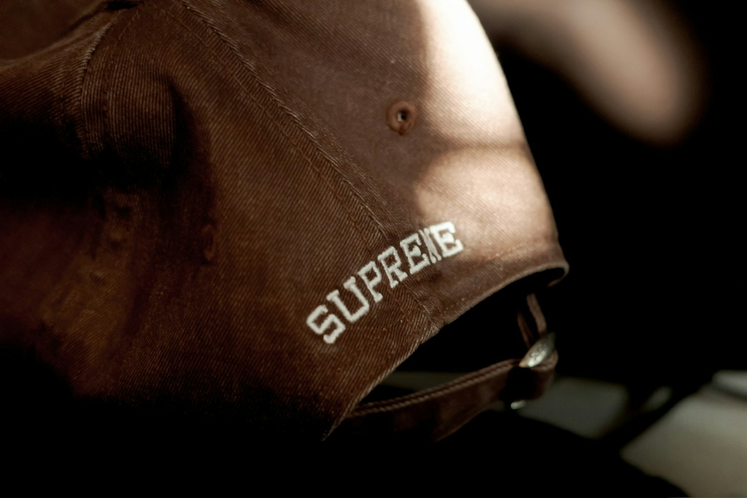 棕色帽子上刺绣着白色的SUPREME字样