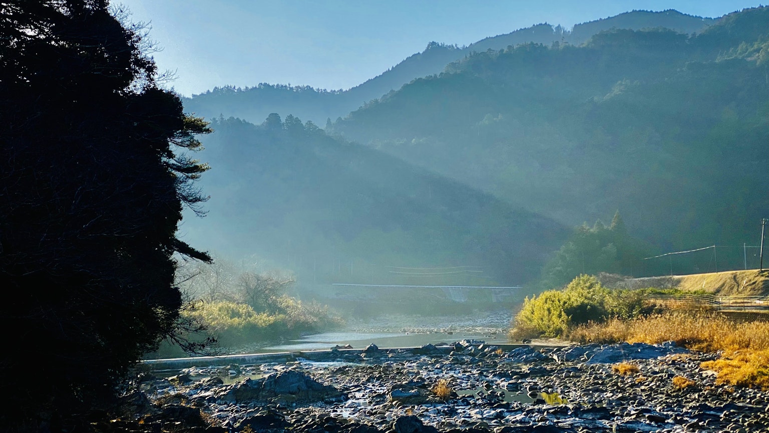 Paisaje sereno de río y montañas con niebla