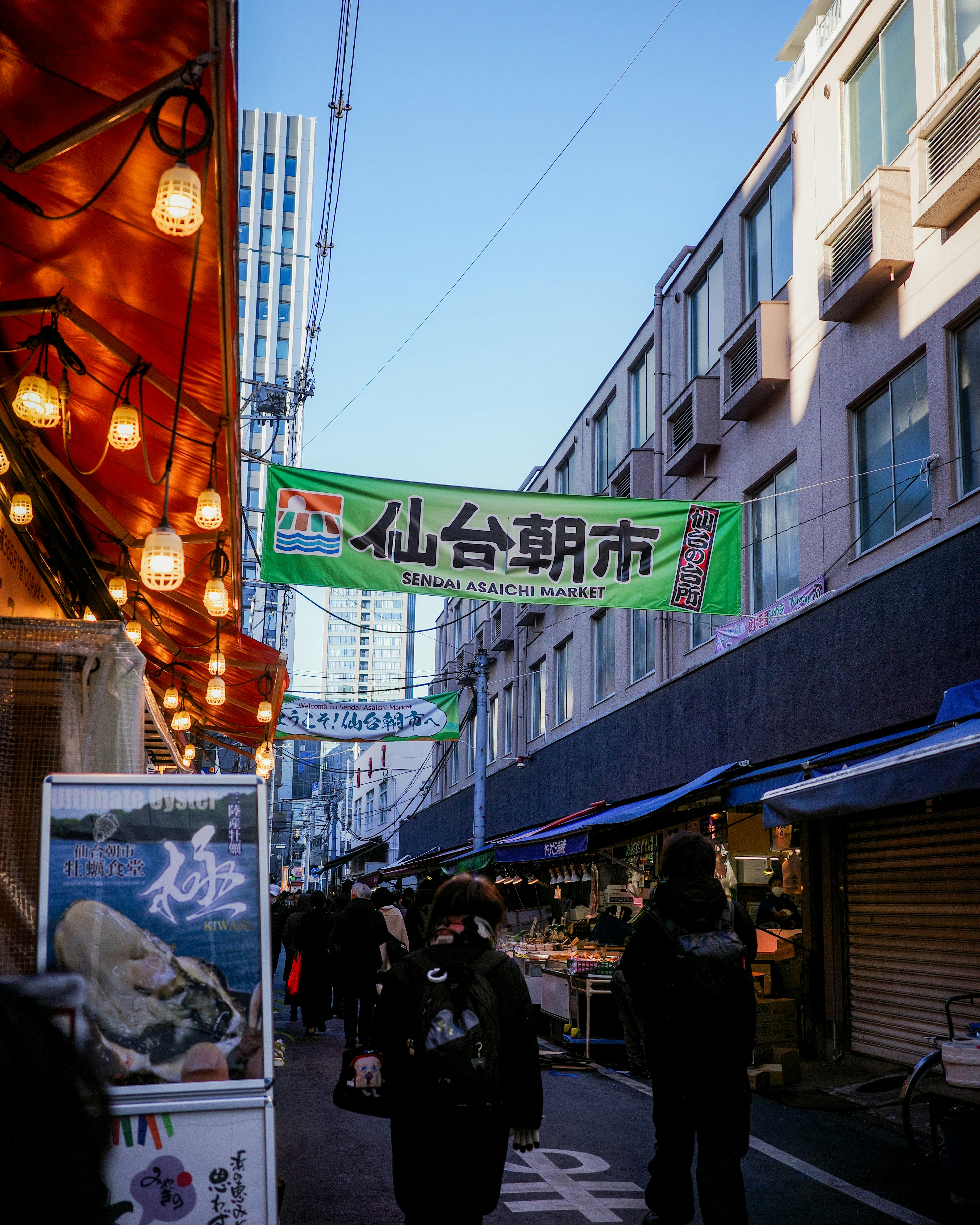 Einkaufsstraße mit Laternen und Ladenfronten, Schild von Sendai Asaichi