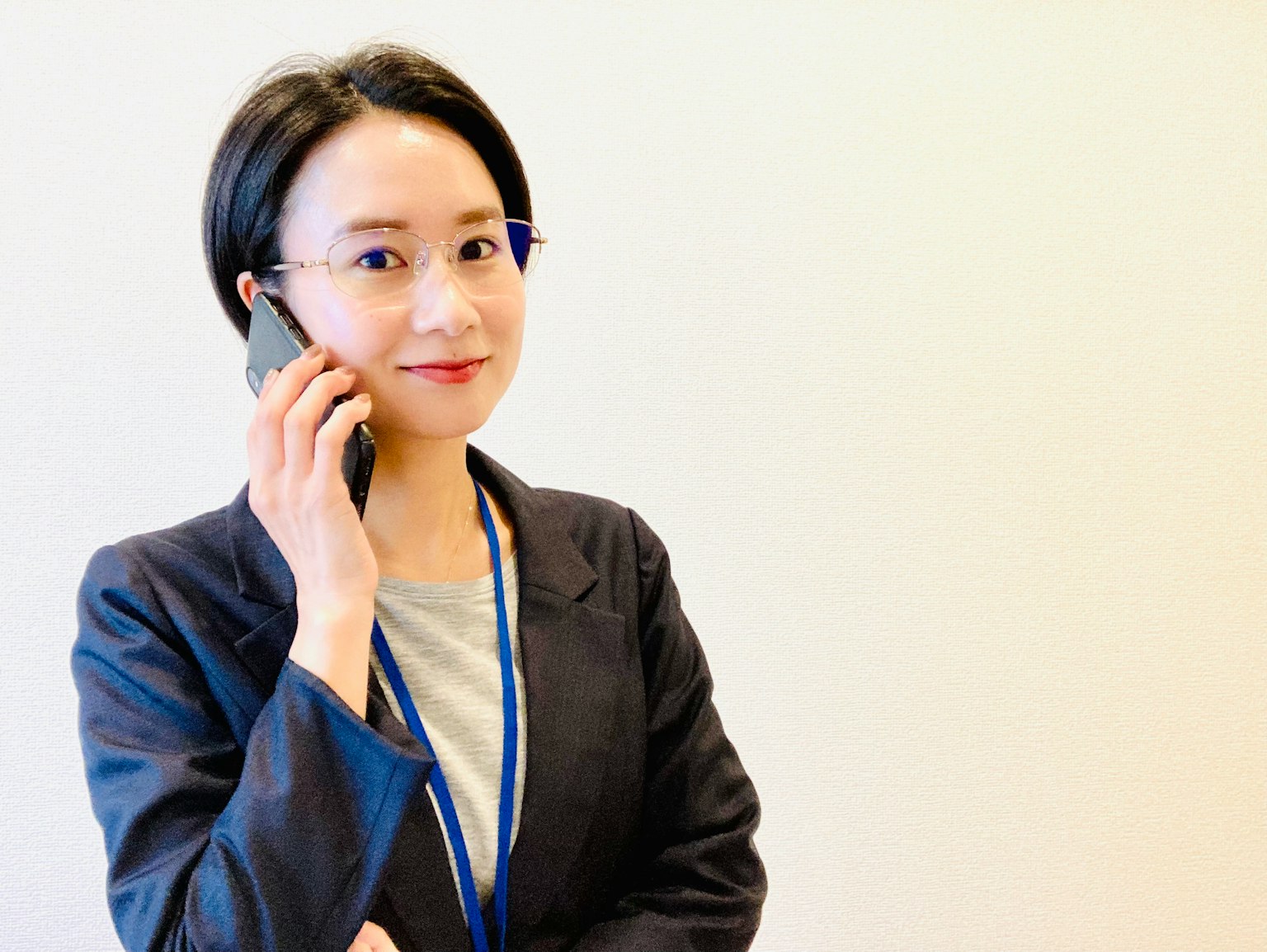 打电话的女商人，穿着黑色西装和蓝色领带，现代办公室背景