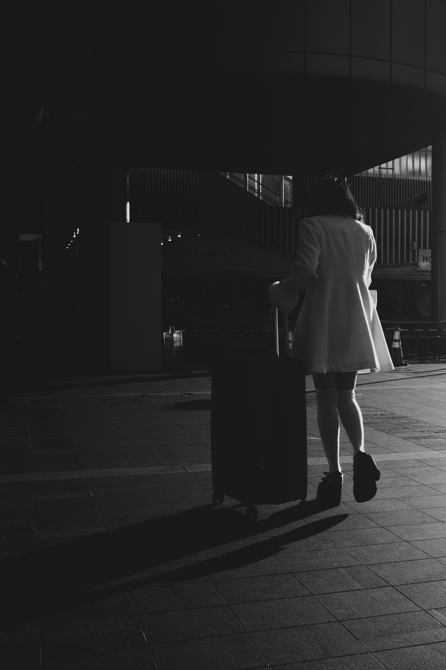 Une femme tirant une valise la nuit dans une ville