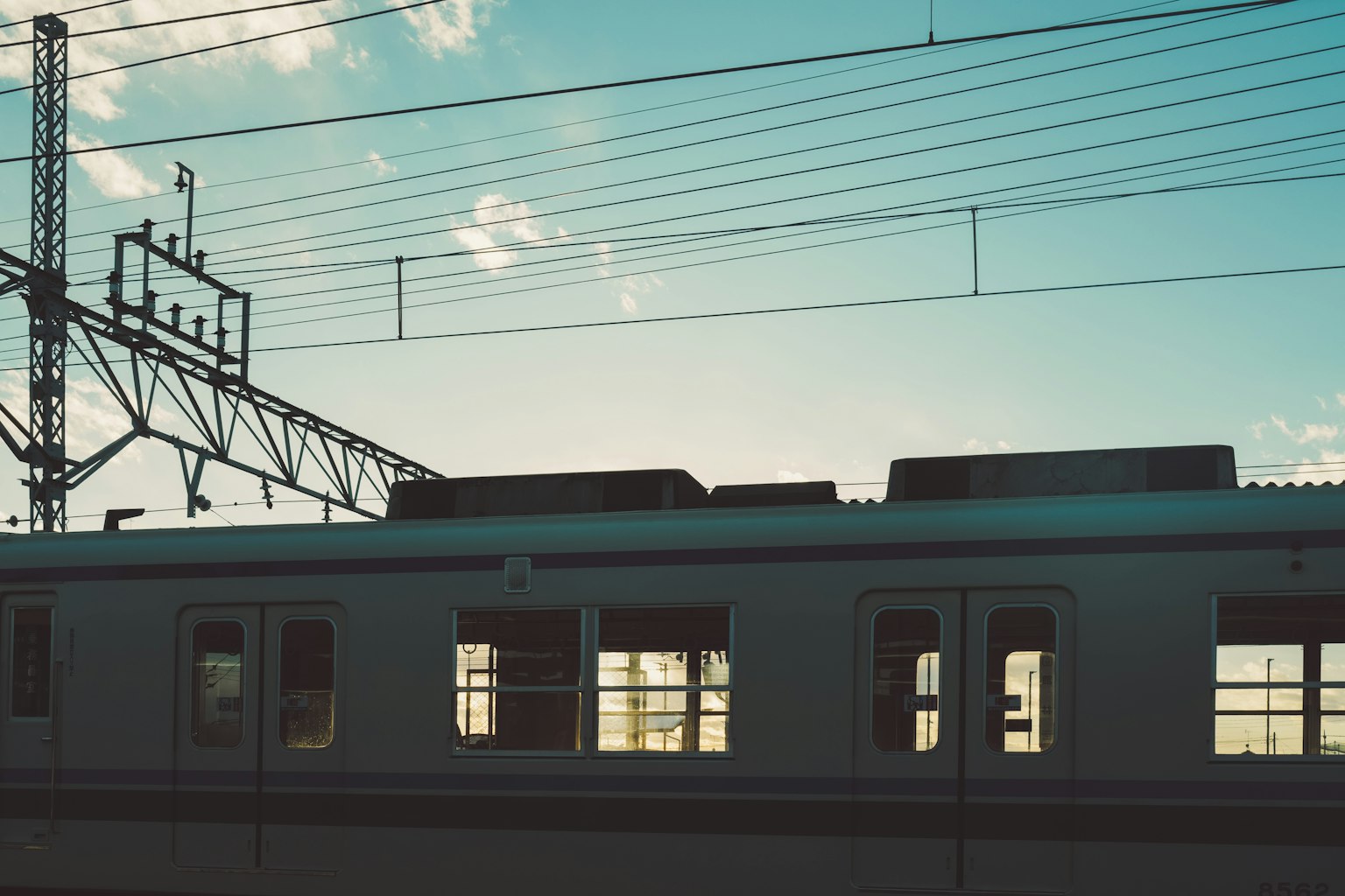 黃昏時的火車輪廓和架空電線