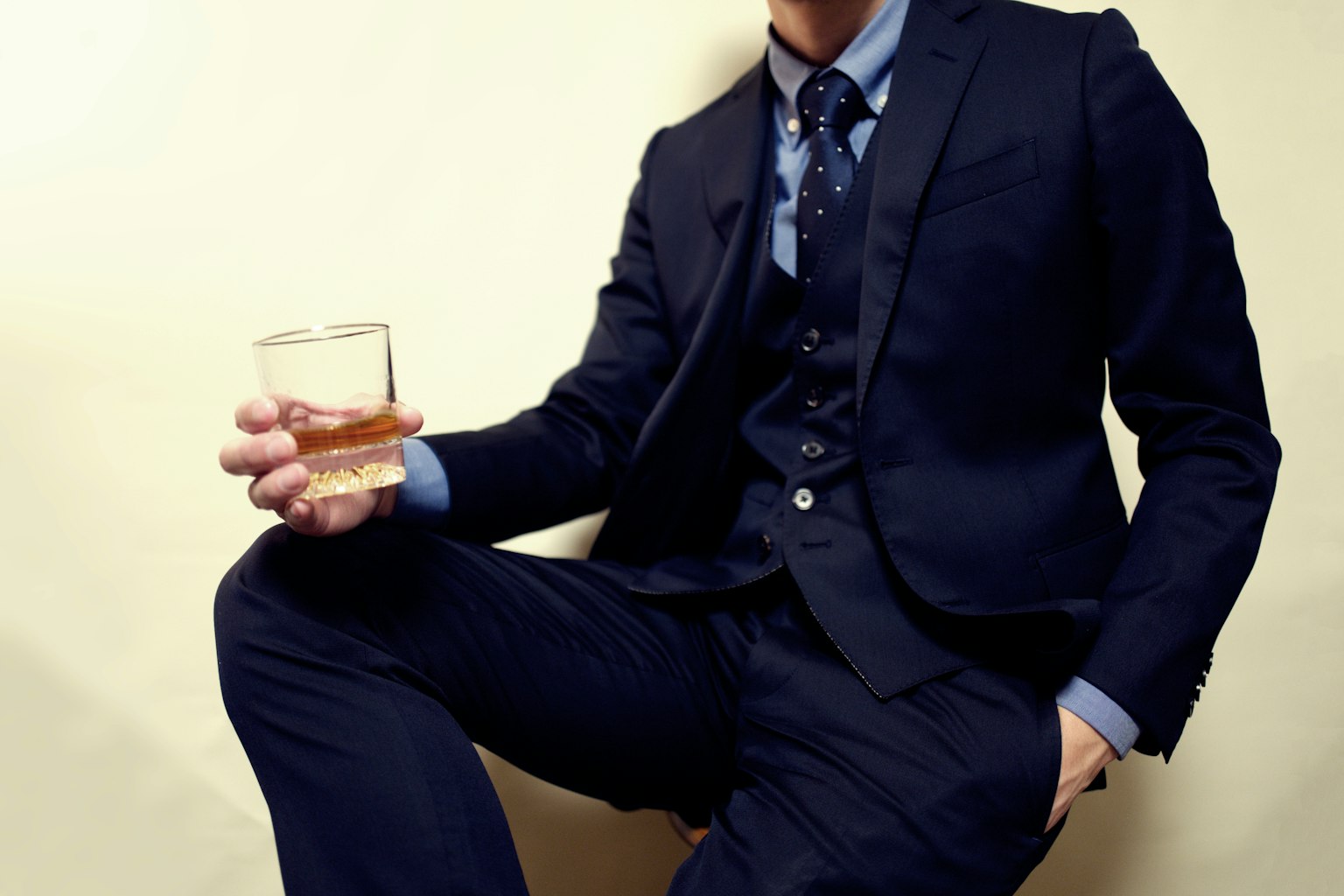 Hombre en traje sosteniendo un vaso de whisky