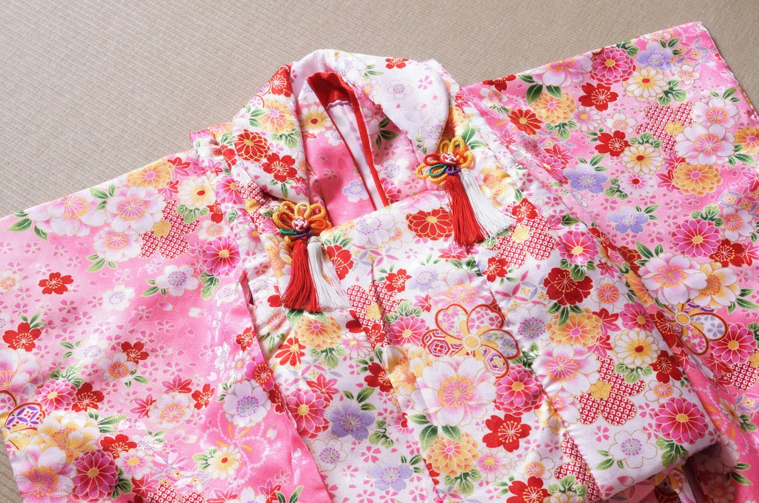 Bunter, blumenmusternder, rosa Kimono mit roten Bändern