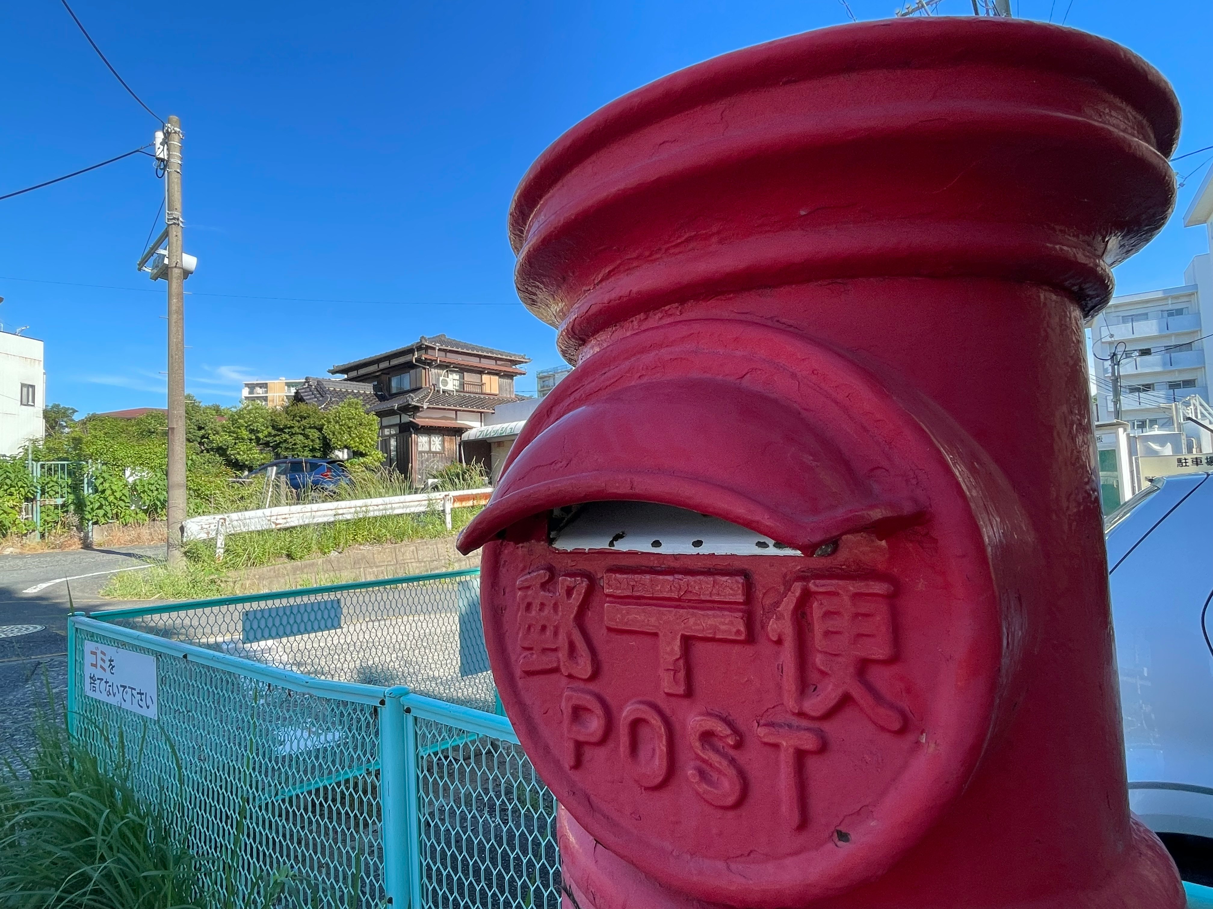 赤いポストの投函口と「POST」刻印のある街角