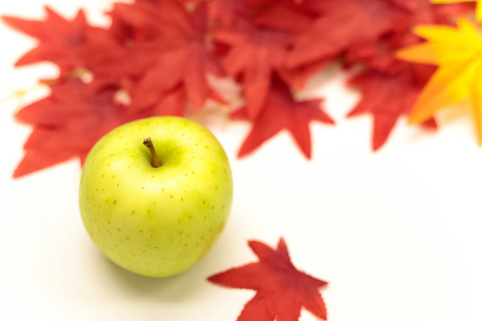 Pomme verte sur un fond de feuilles rouges et jaunes