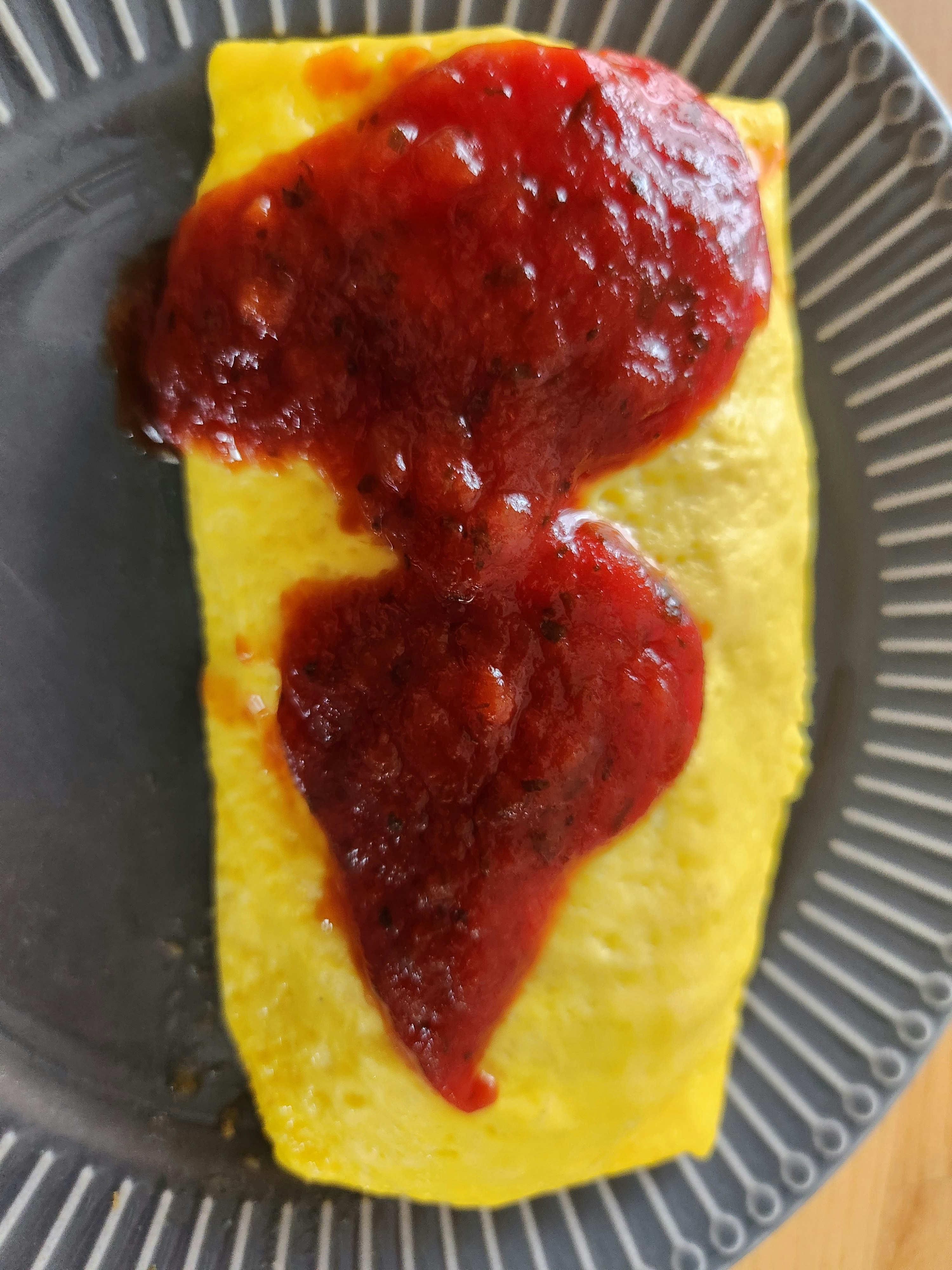 Plat jaune type omelette recouvert d’une sauce rouge