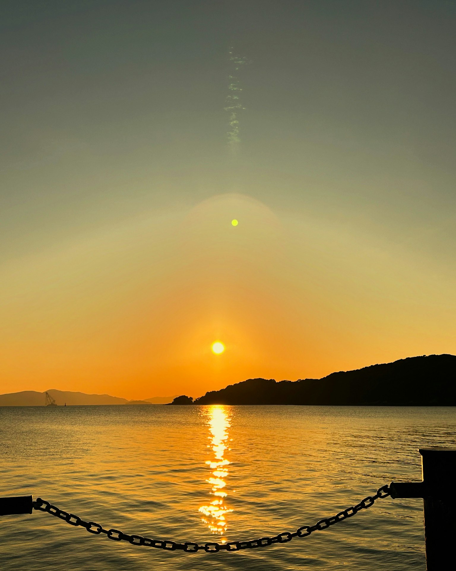 Hermoso paisaje marítimo con el atardecer reflejándose en el agua y silueta de montañas