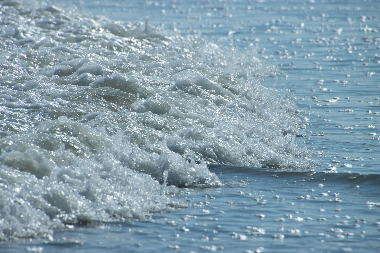 Vagues se brisant sur une mer bleue avec des bulles scintillantes et des reflets