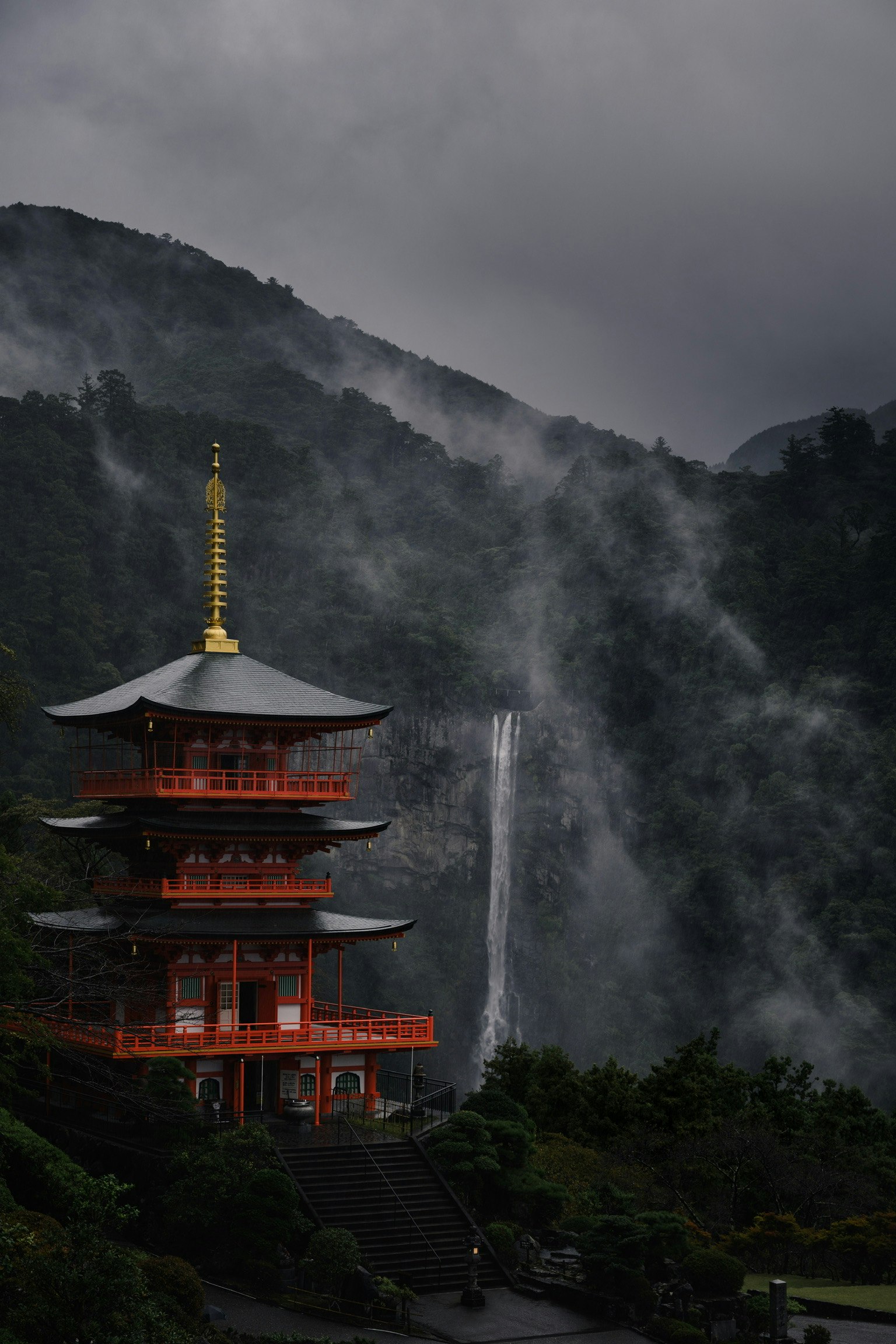 Pagoda rossa circondata da montagne nebbiose e una cascata