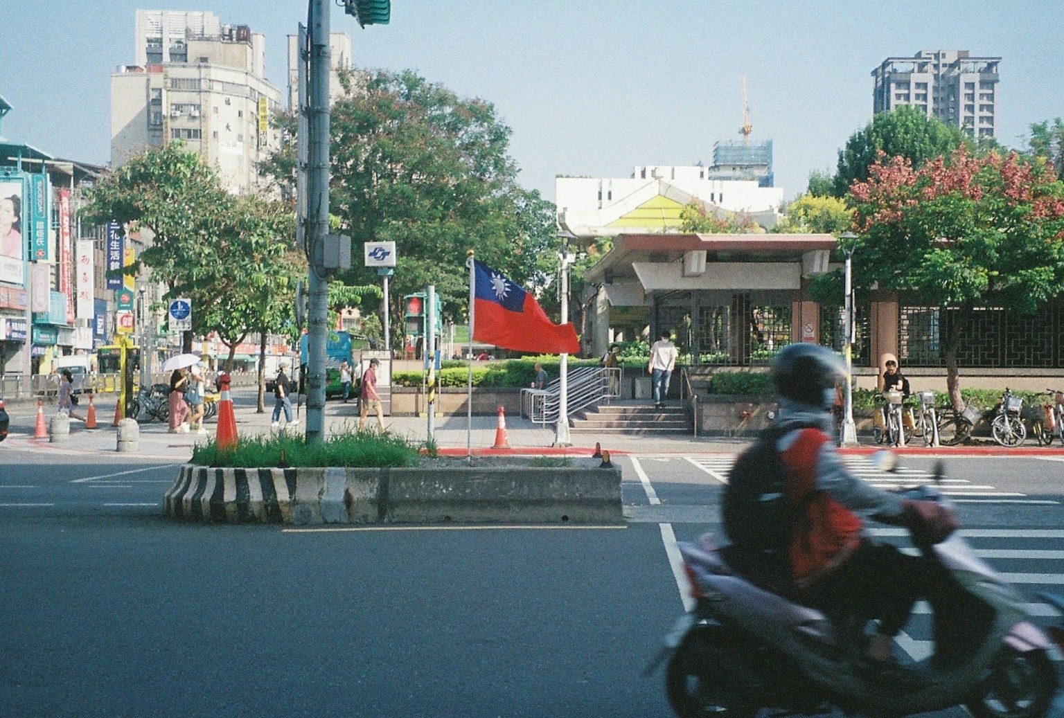 Escena de calle en Taipei con una motocicleta pasando y la bandera de Taiwán visible