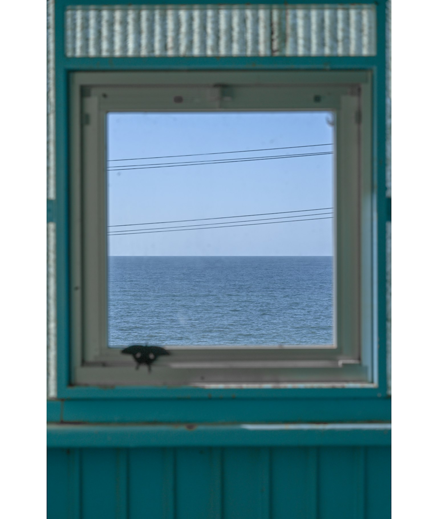 View of the ocean through a turquoise window frame