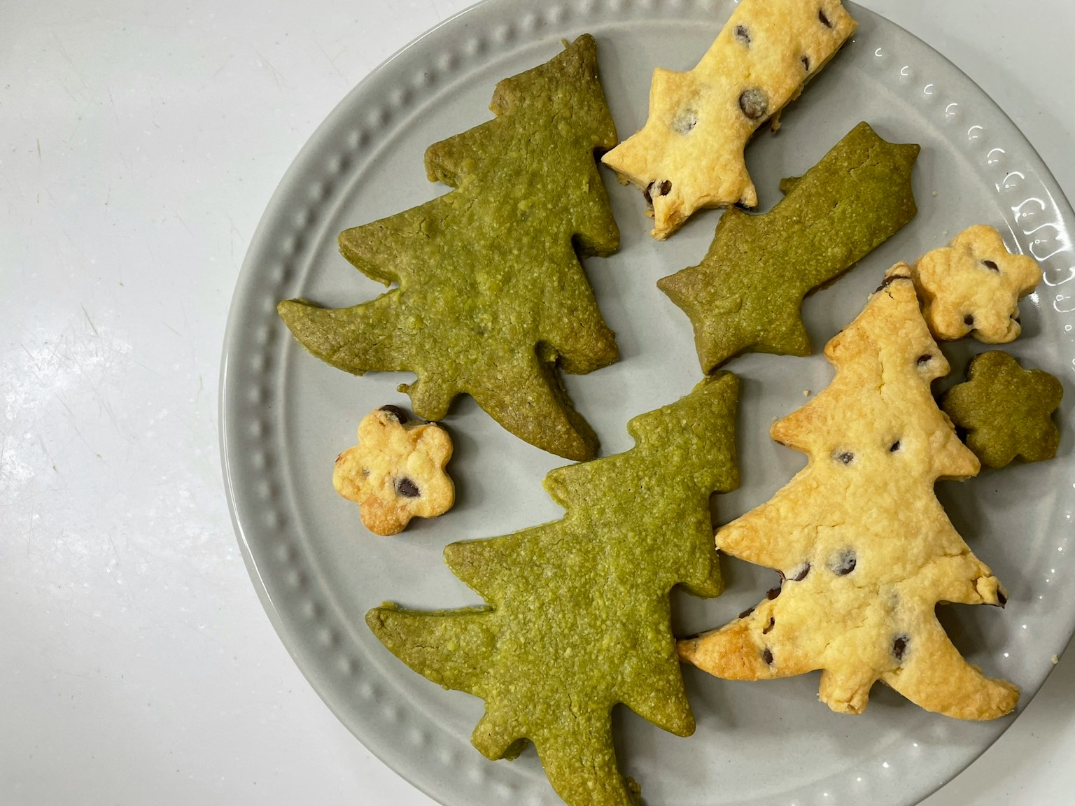 Galletas en forma de árbol de Navidad verdes y galletas en forma de estrella dispuestas en un plato