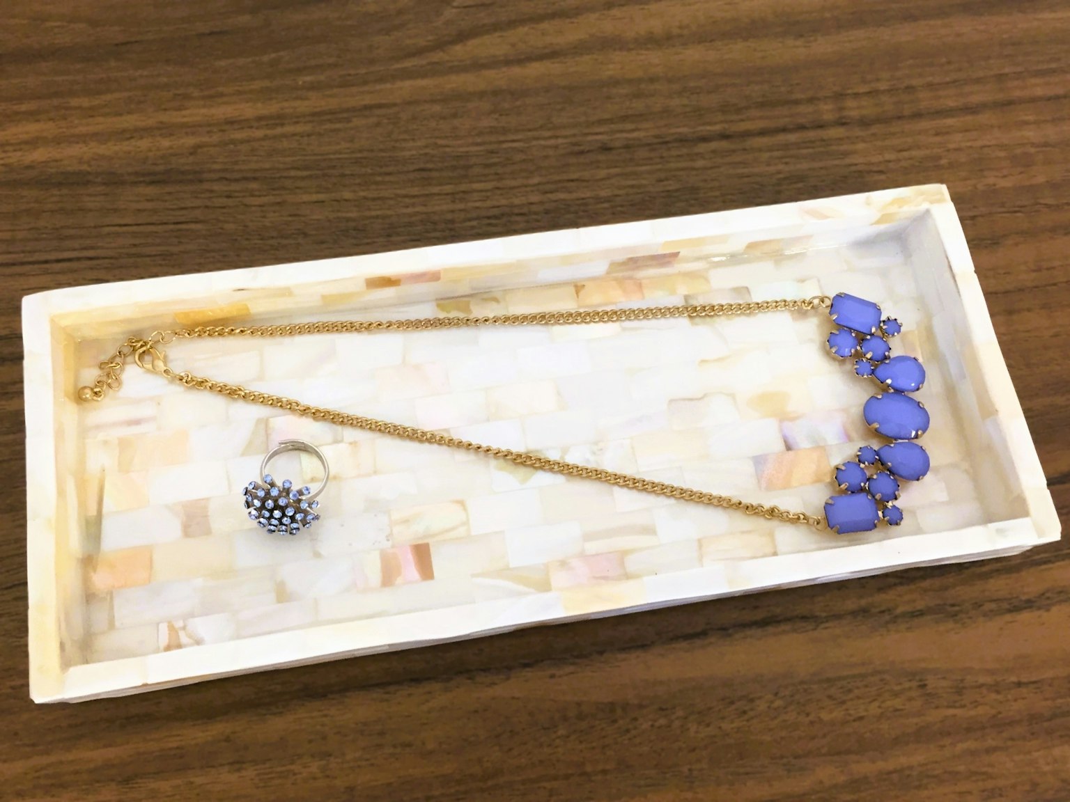 Collana e anello di gioielli posati su un vassoio bianco