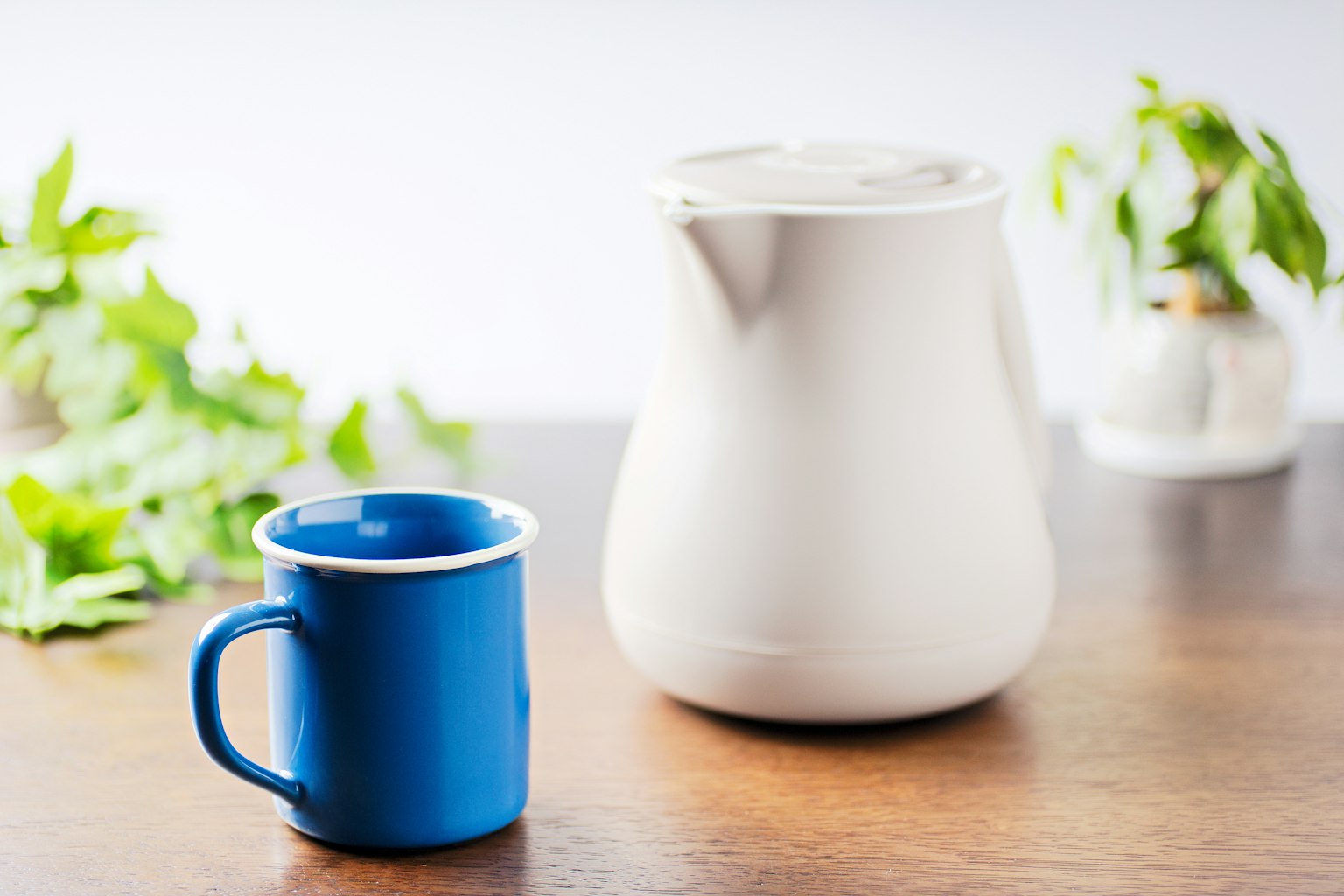 A blue mug and a white pitcher placed on a wooden table