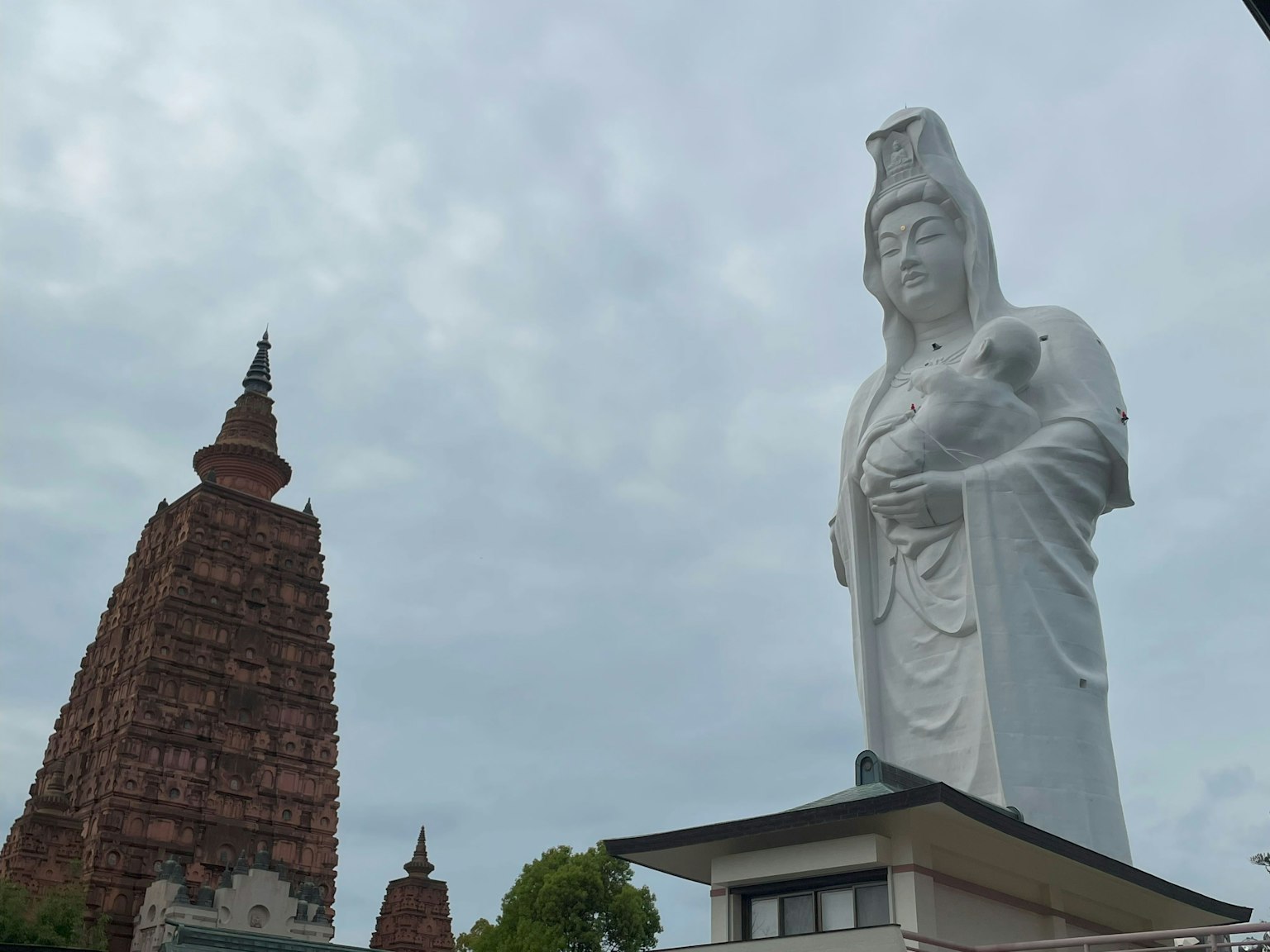 Grande statue de Guanyin à côté d'une pagode ancienne