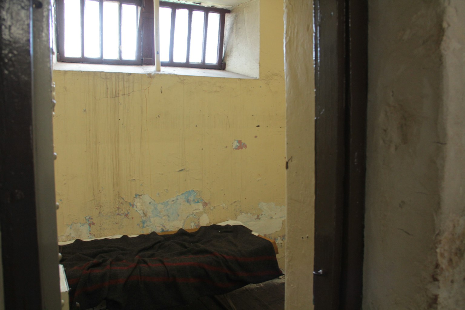 Una habitación pequeña con paredes amarillas que tiene una ventana y una cama