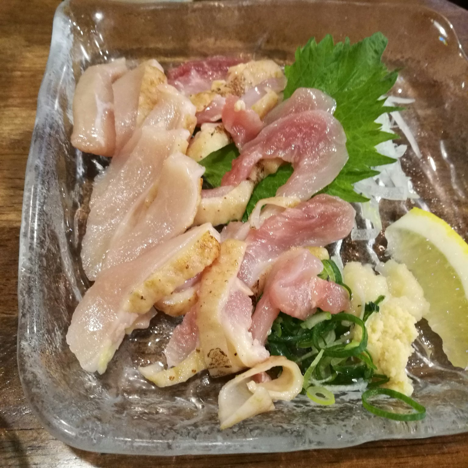 切片生鸡肉放在盘子里，配有柠檬和配菜