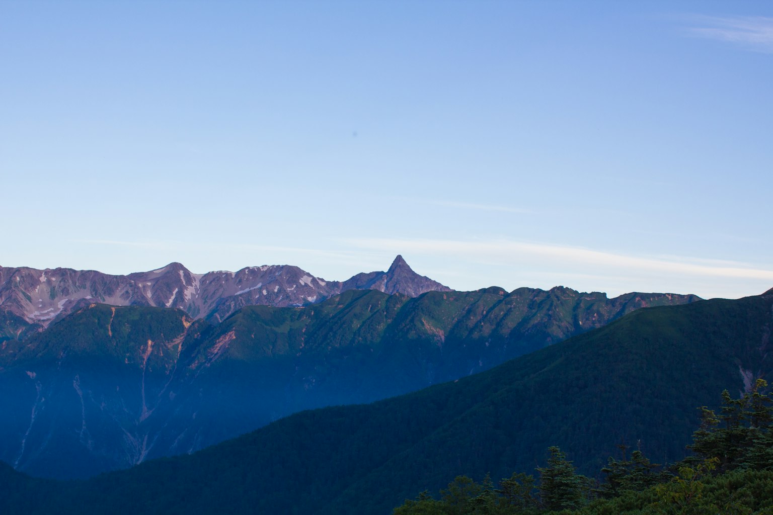Eine malerische Aussicht auf Berge unter einem blauen Himmel mit einem markanten Gipfel