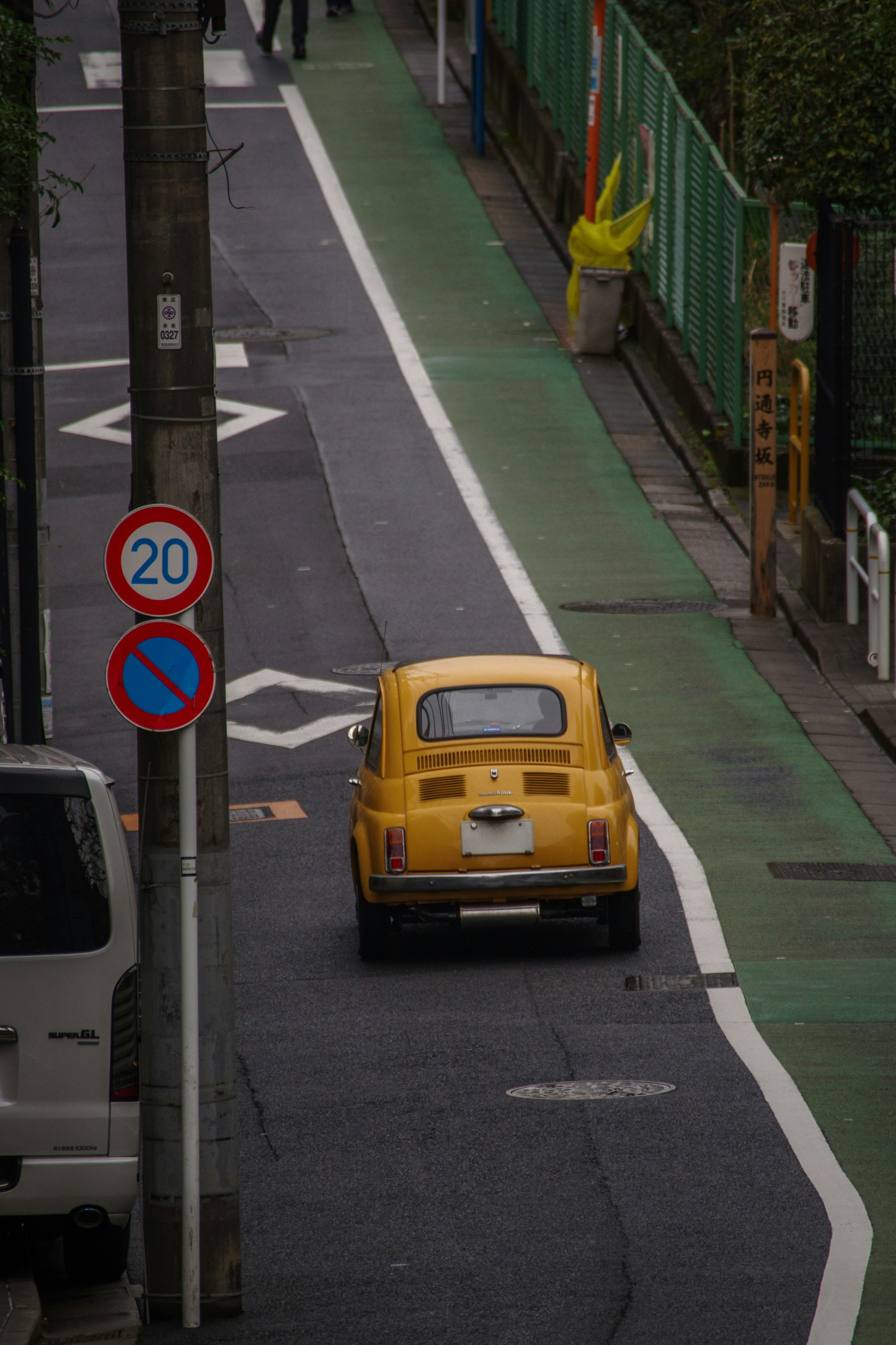 petite voiture jaune ronde roulant dans une rue étroite