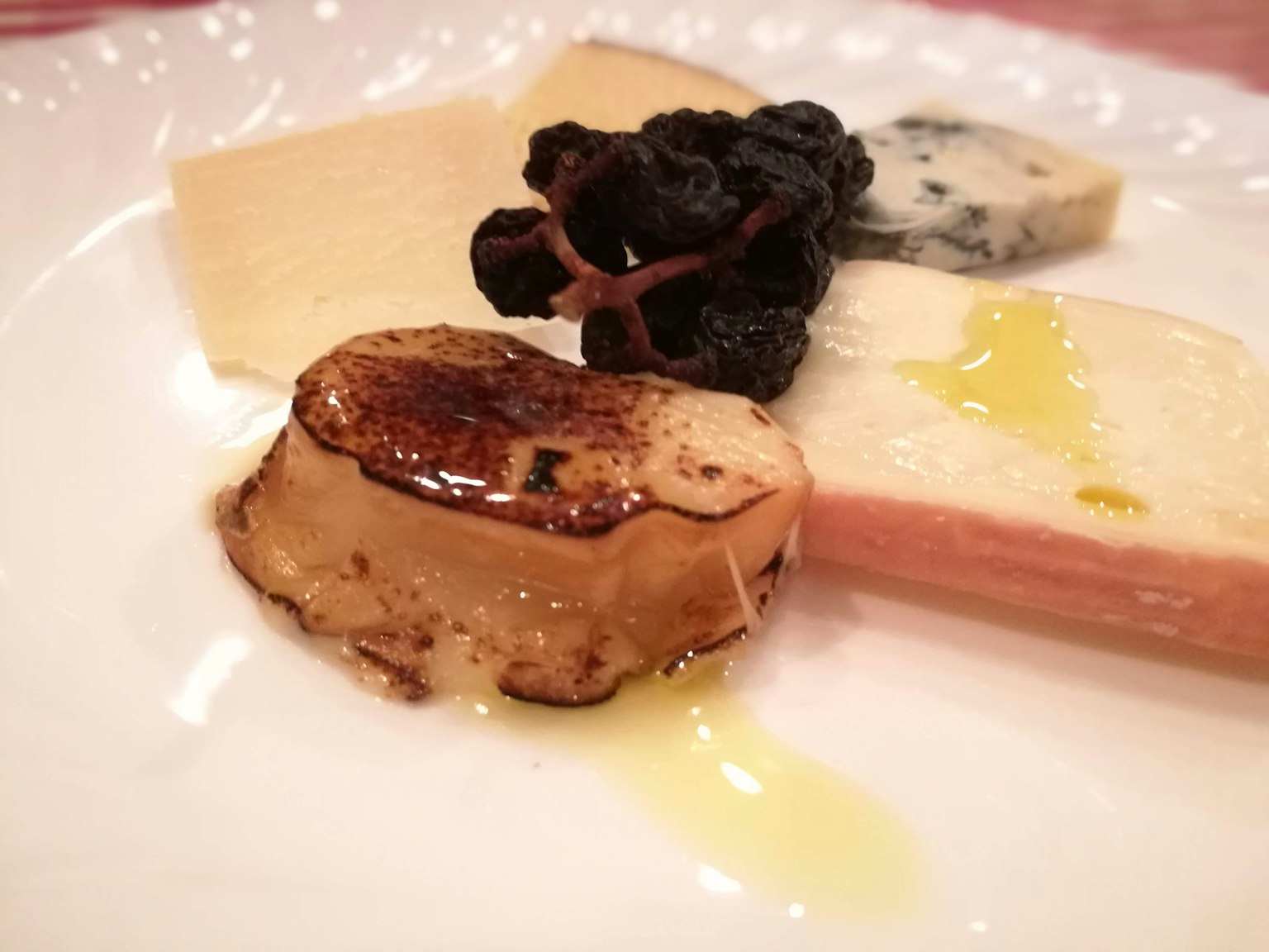 Foie gras grigliato su un piatto con formaggio, olio d'oliva e funghi neri essiccati