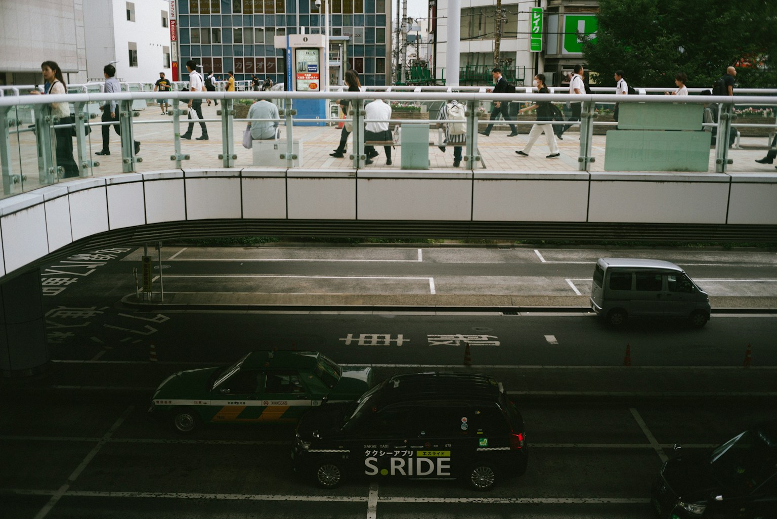 View of a pedestrian bridge with people walking and vehicles on the road
